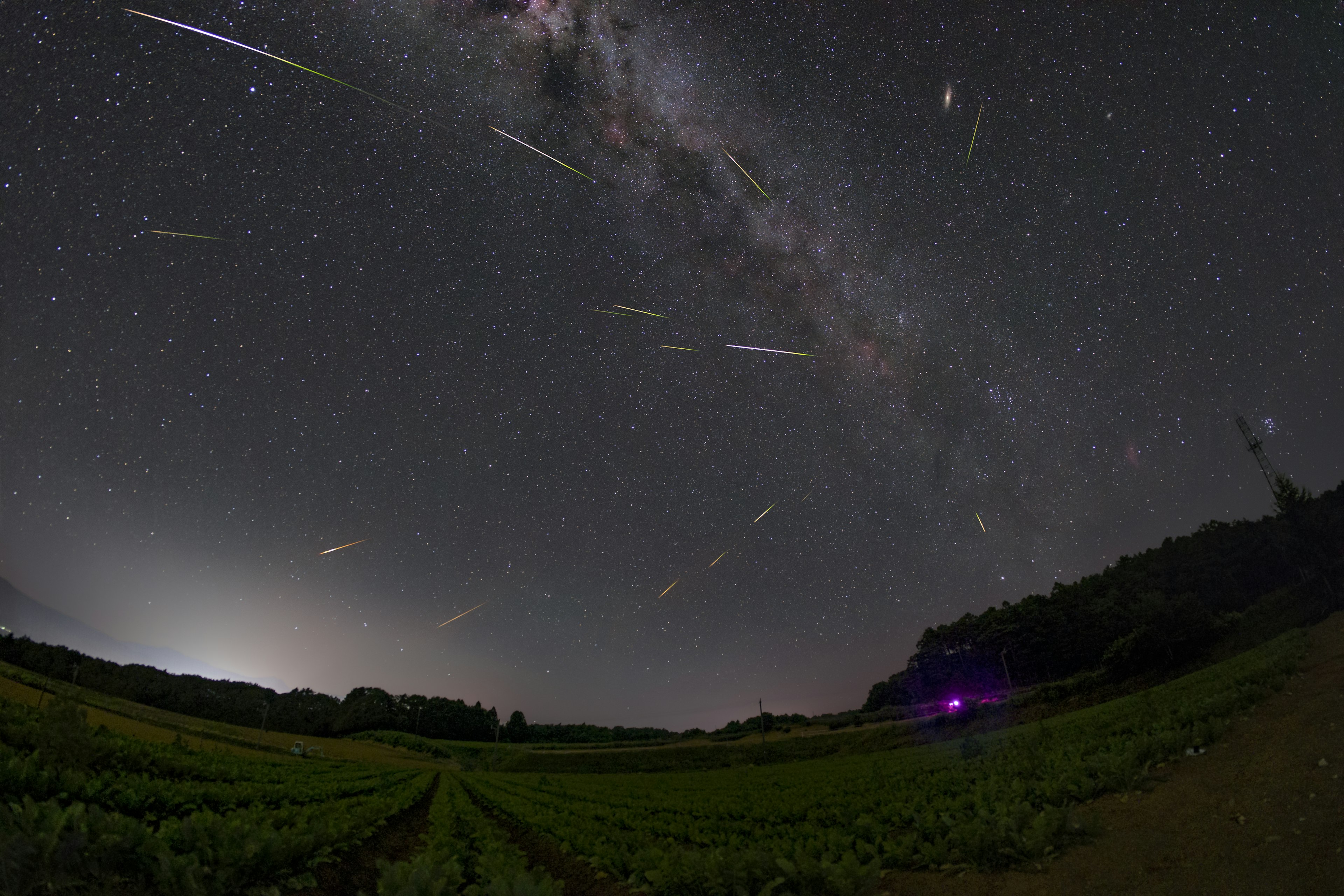 星空の下で流れ星が輝く風景と銀河が見える