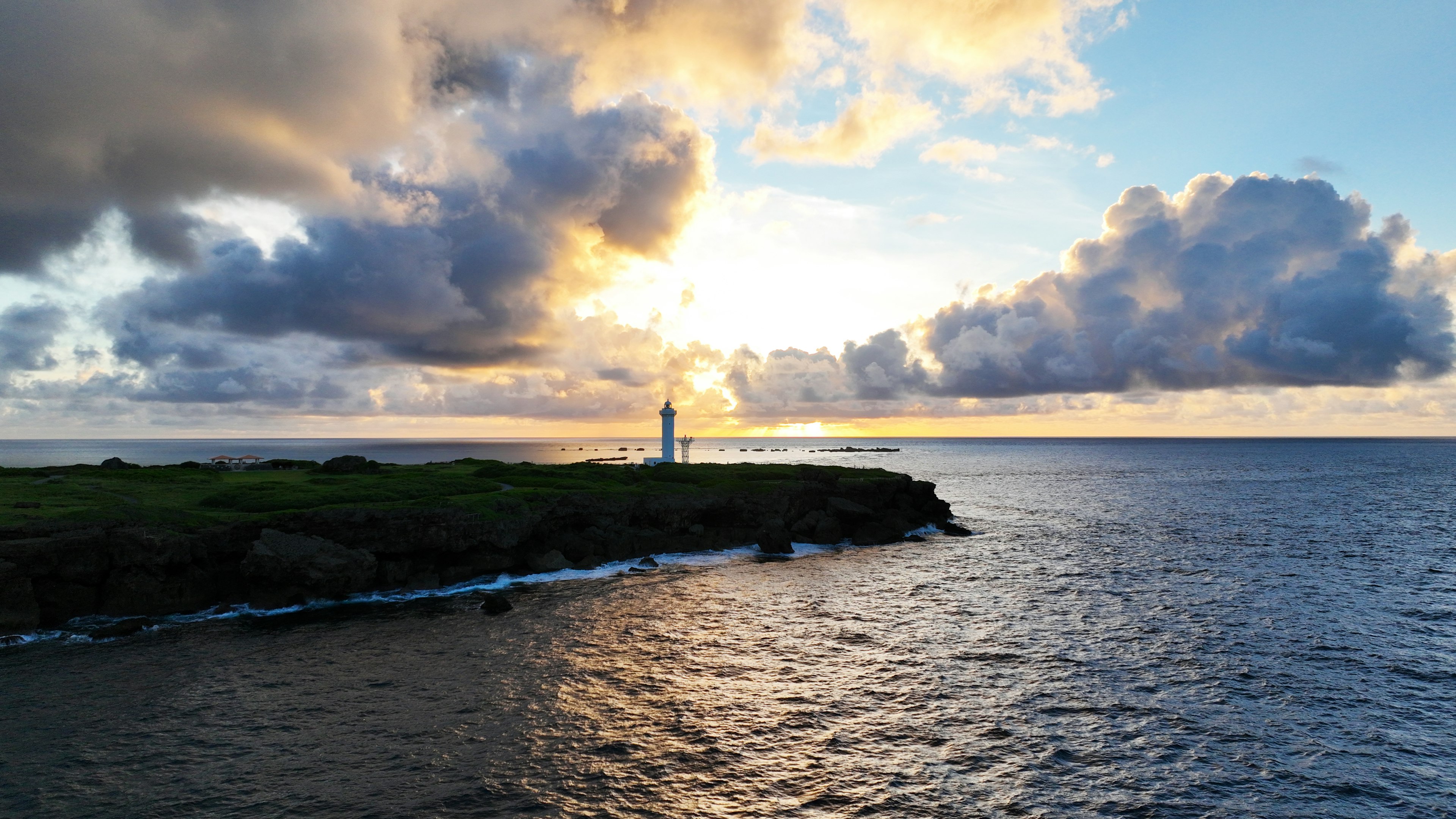 Faro costiero al tramonto con nuvole drammatiche