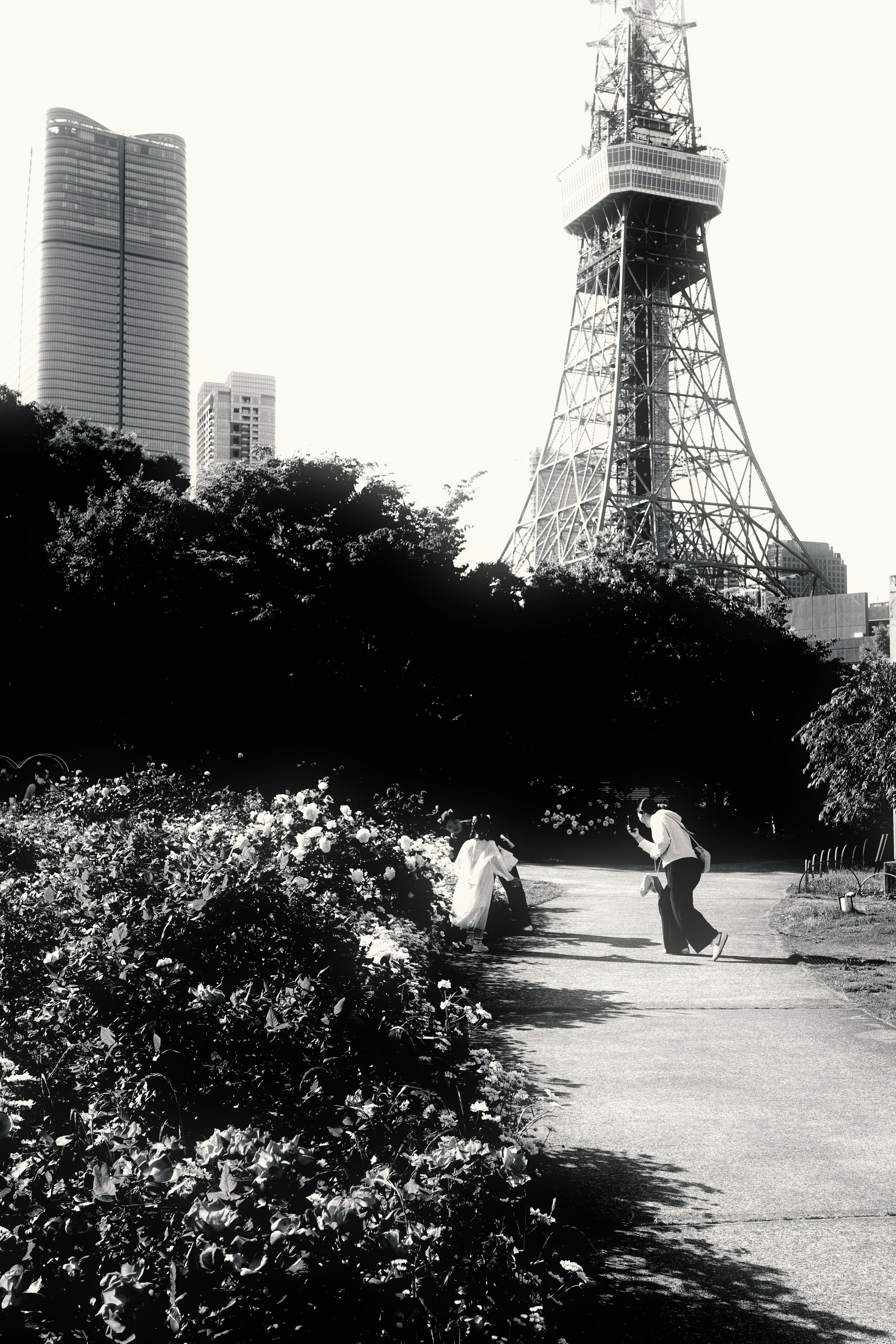 Blick auf den Tokyo Tower von einem Park mit Grünflächen und Menschen