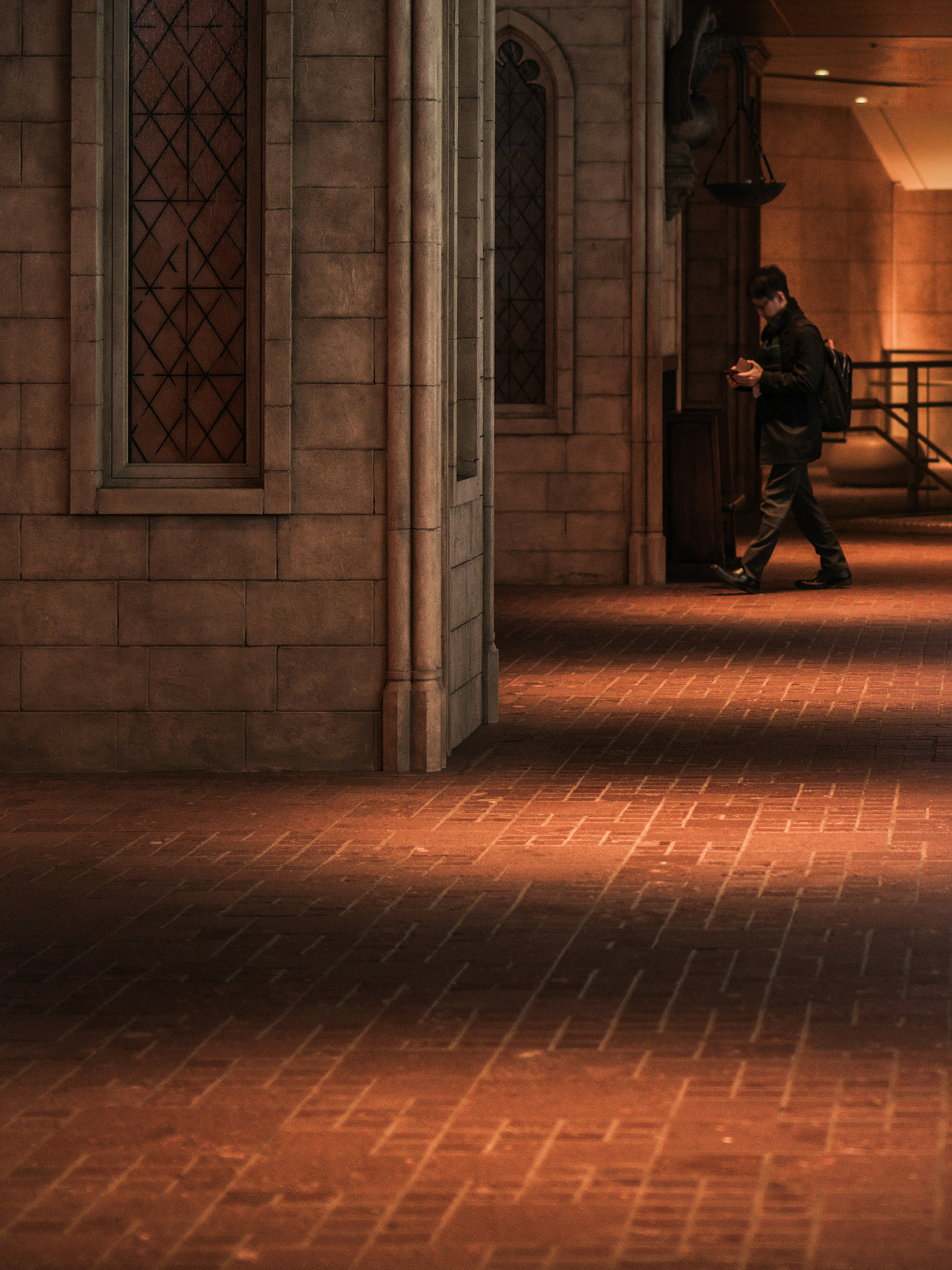 A shadowy corridor with a person walking and stone walls