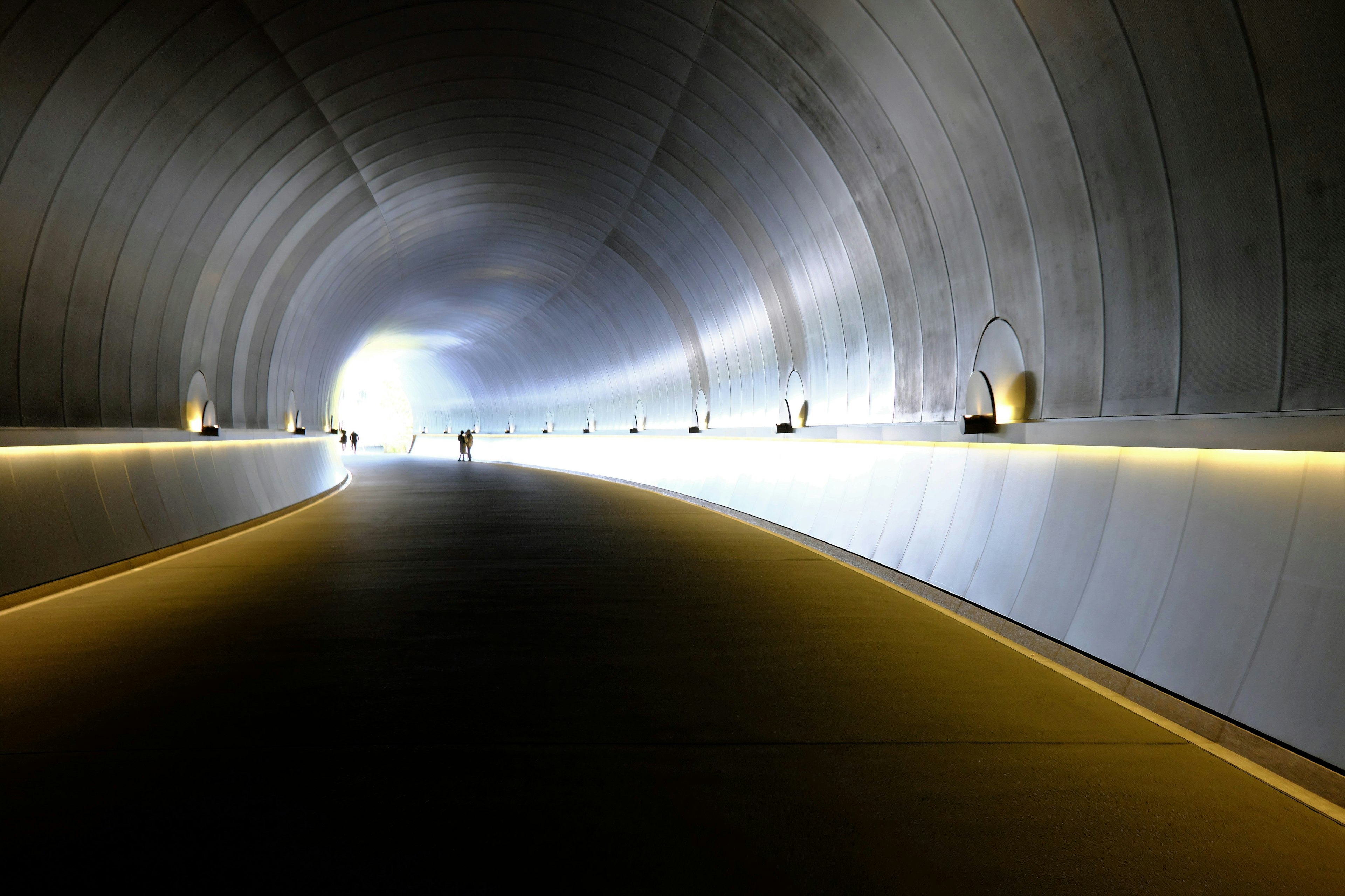 Inneres eines Tunnels, das sich zu einem hellen Ausgang krümmt