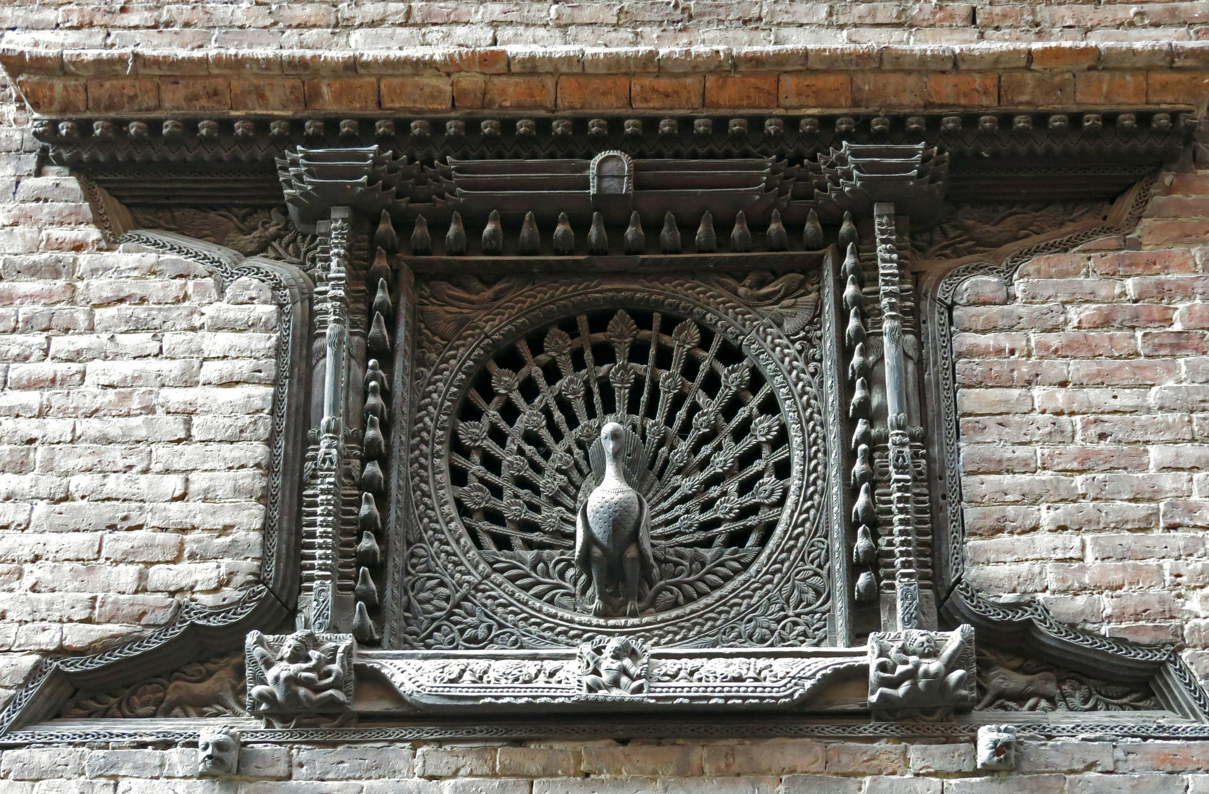 Intricate wooden carved peacock decoration on a window frame