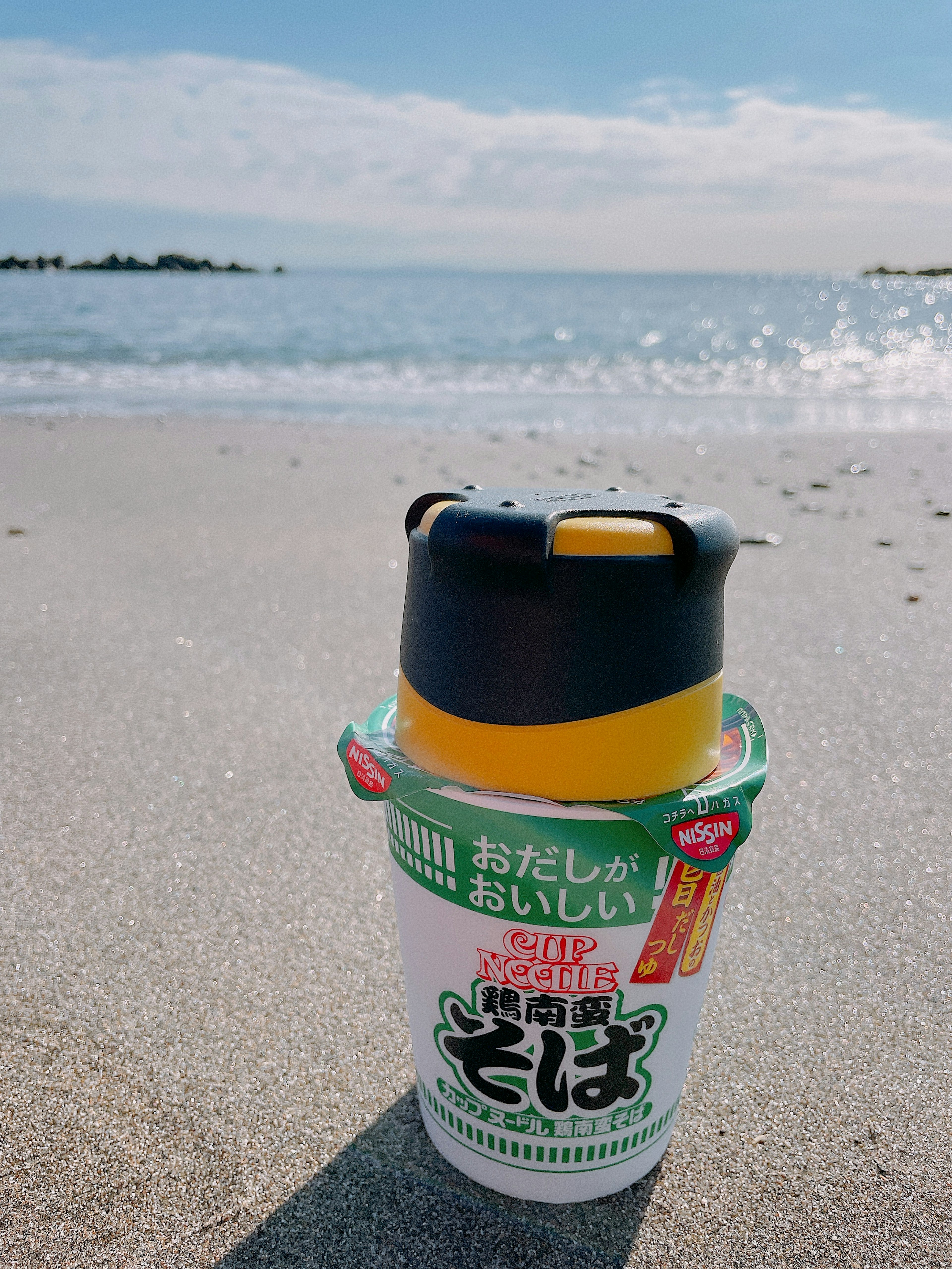 Tasse Soba-Nudeln am Strand mit blauem Himmel