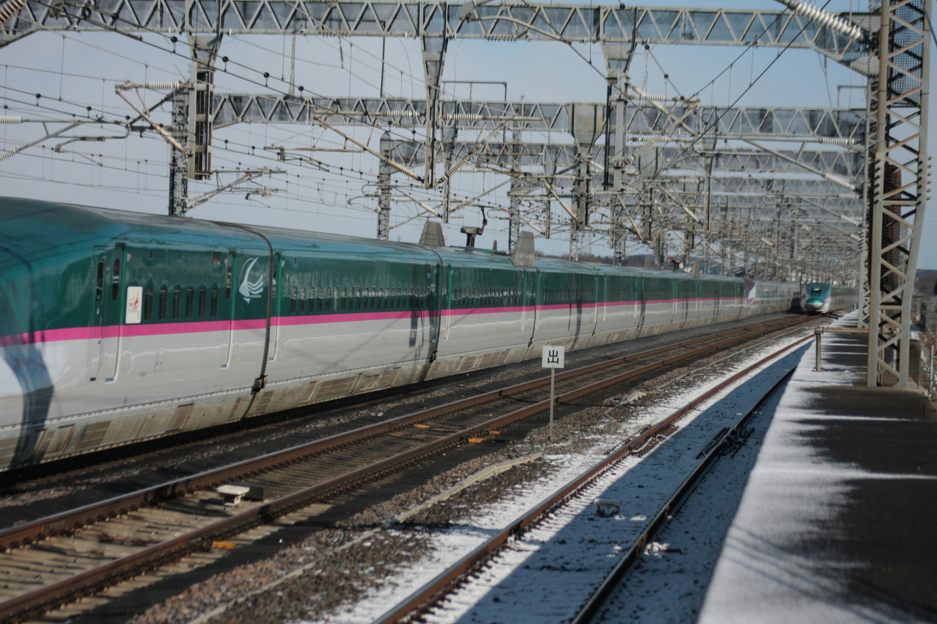 Shinkansen train traveling through a snowy landscape with railway tracks