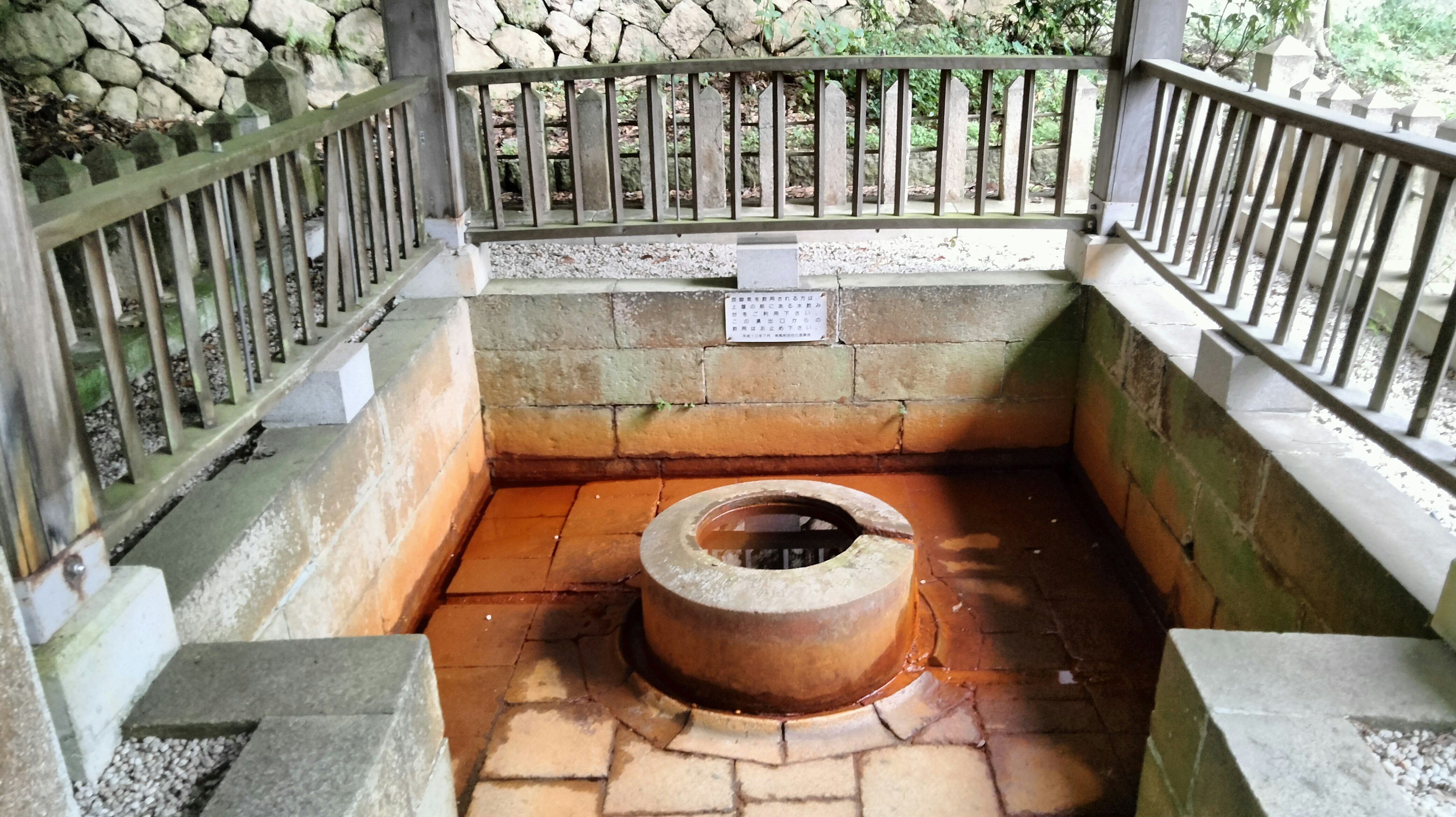 Traditional well in a covered structure surrounded by wooden railing and stone walls