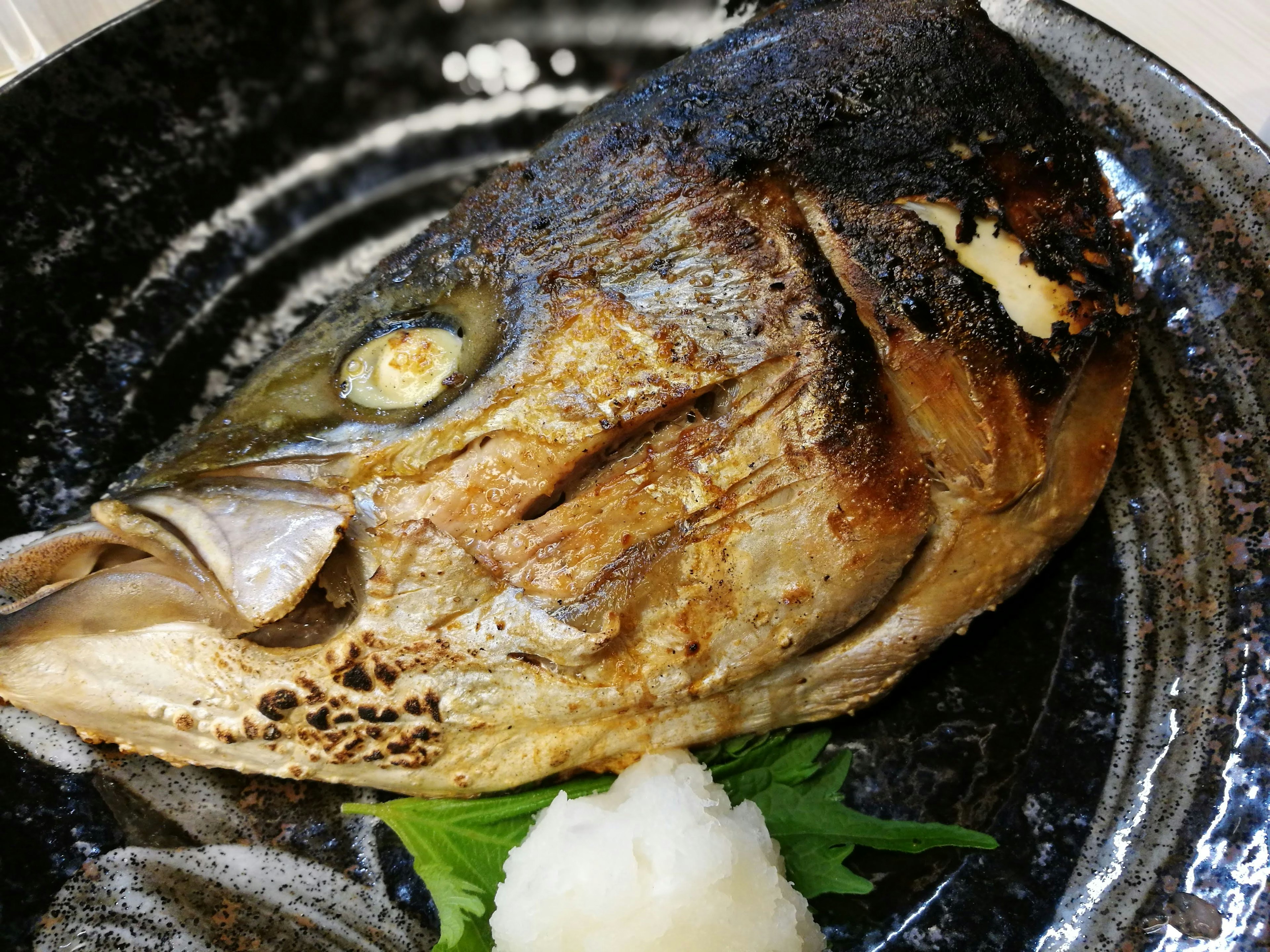 Cabeza de pescado a la parrilla servida con daikon rallado y verduras