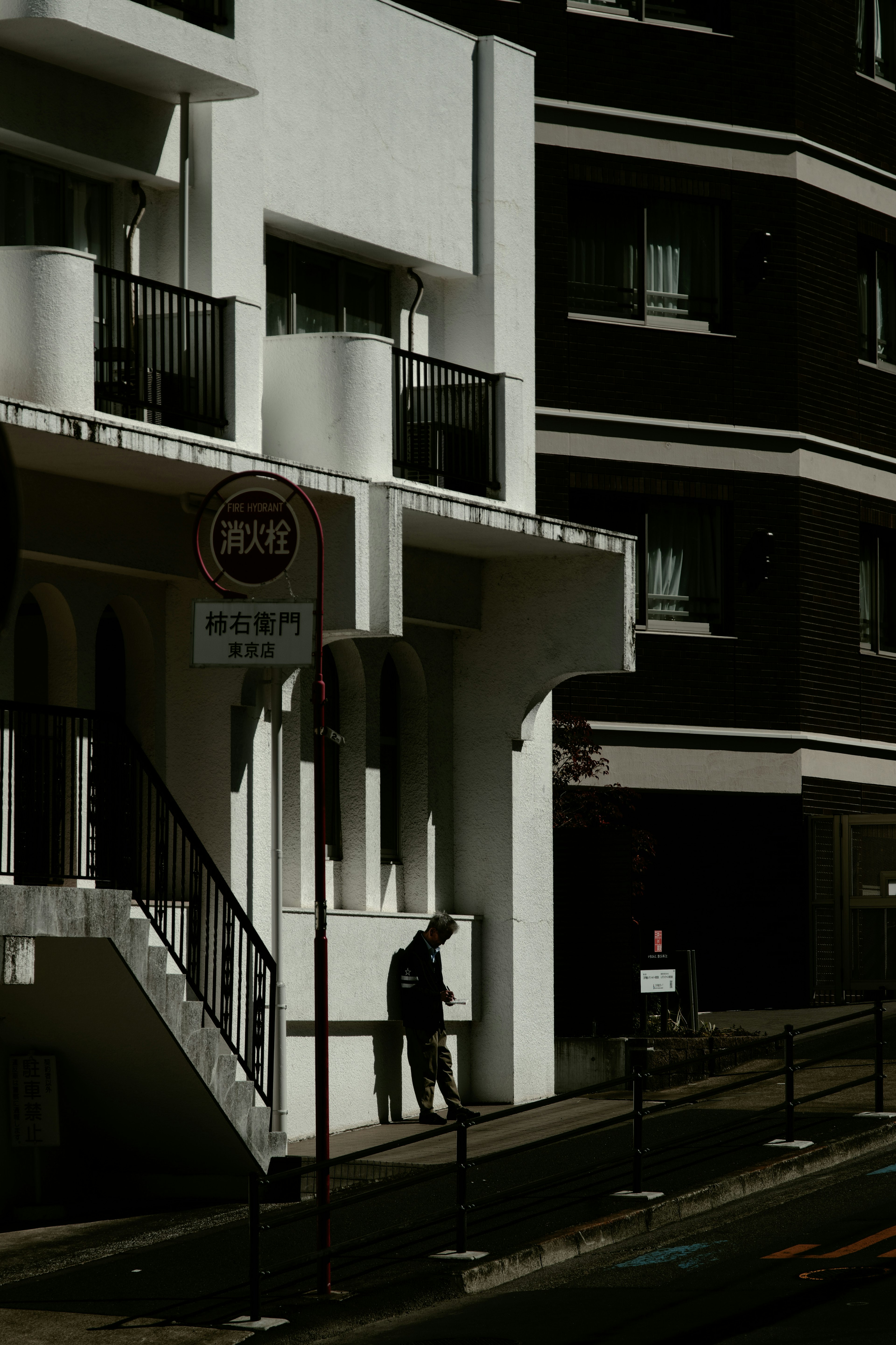 Una persona in piedi a un angolo di strada con edifici bianchi e neri a contrasto