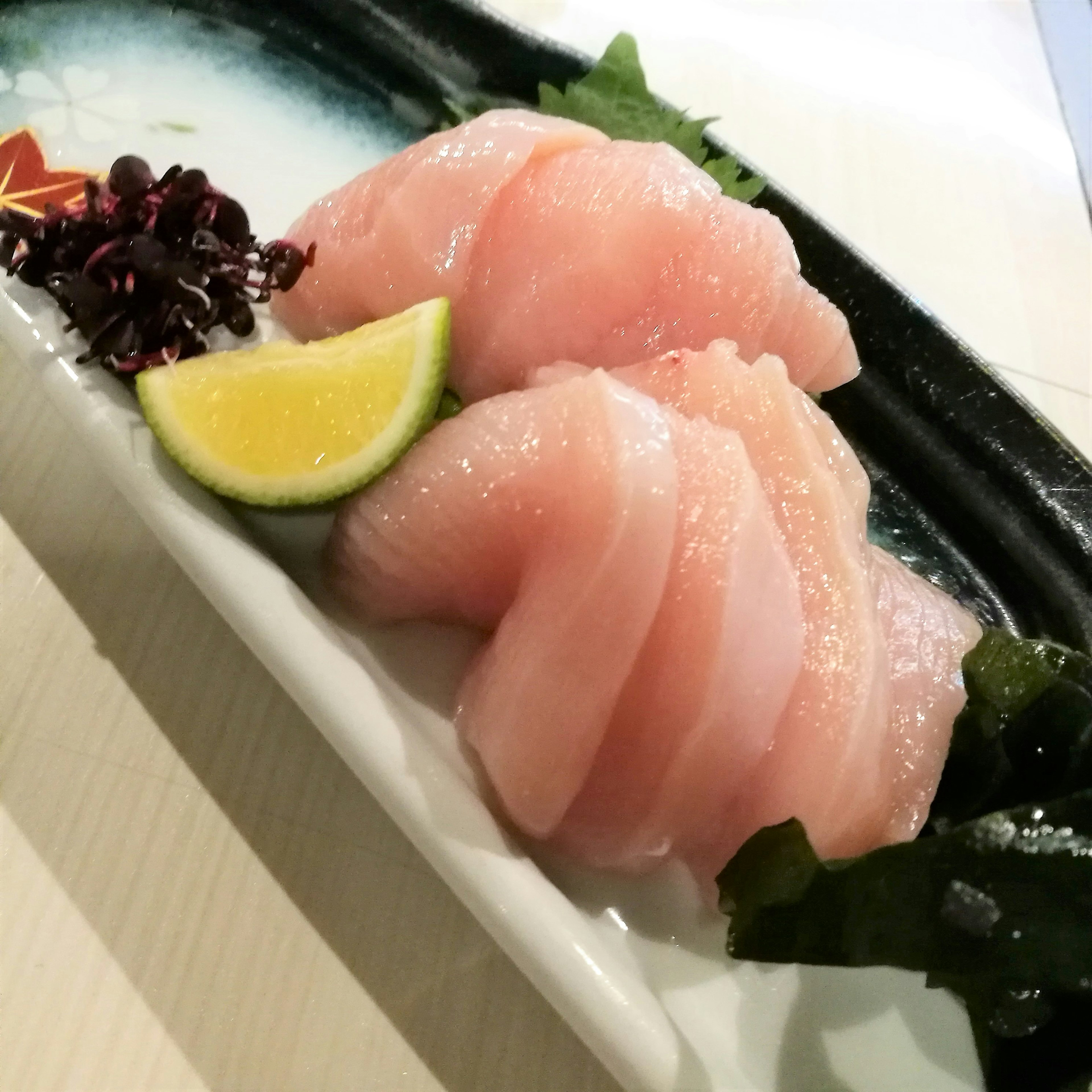 Fresh sashimi platter featuring thinly sliced fish with lemon and seaweed