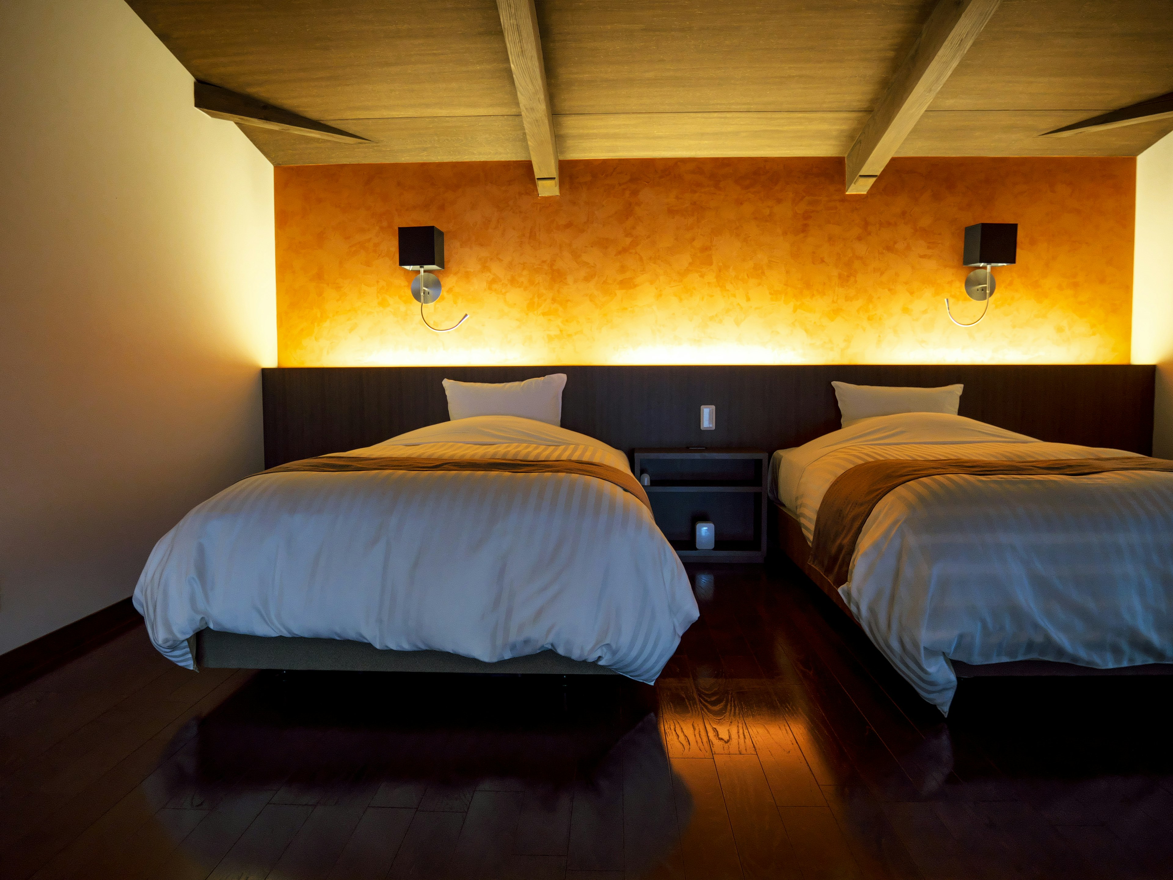 Une chambre moderne et simple avec deux lits mur orange chaud et éclairage d'ambiance