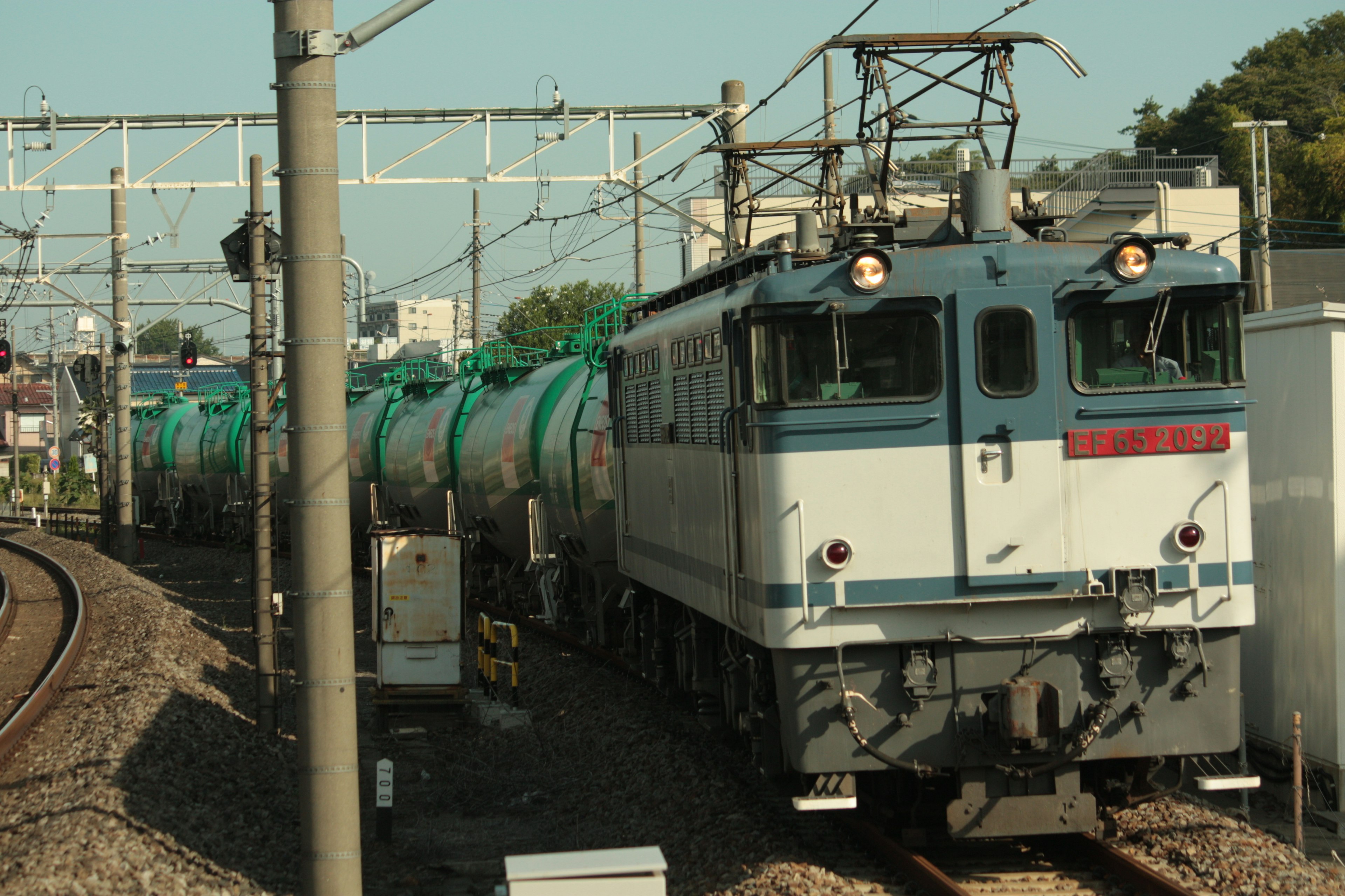 Electric locomotive pulling blue tank cars on a railway track