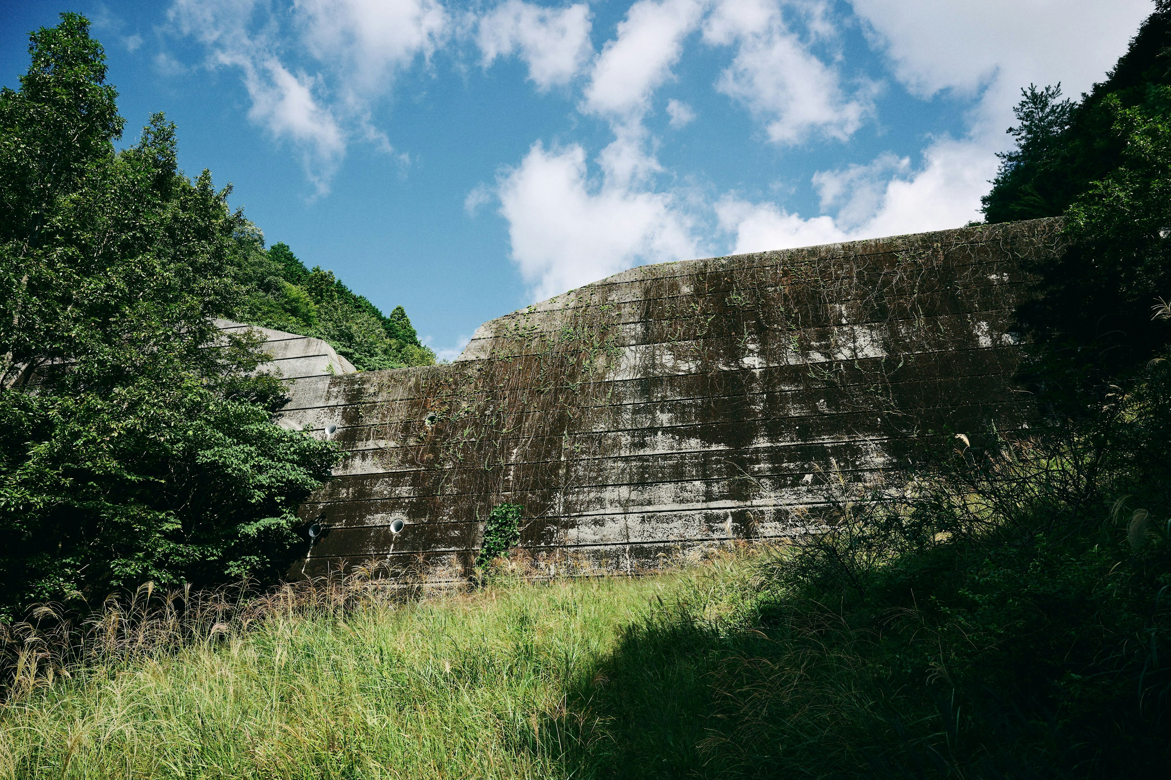 Alter Betonmauer umgeben von grünem Gras und blauem Himmel