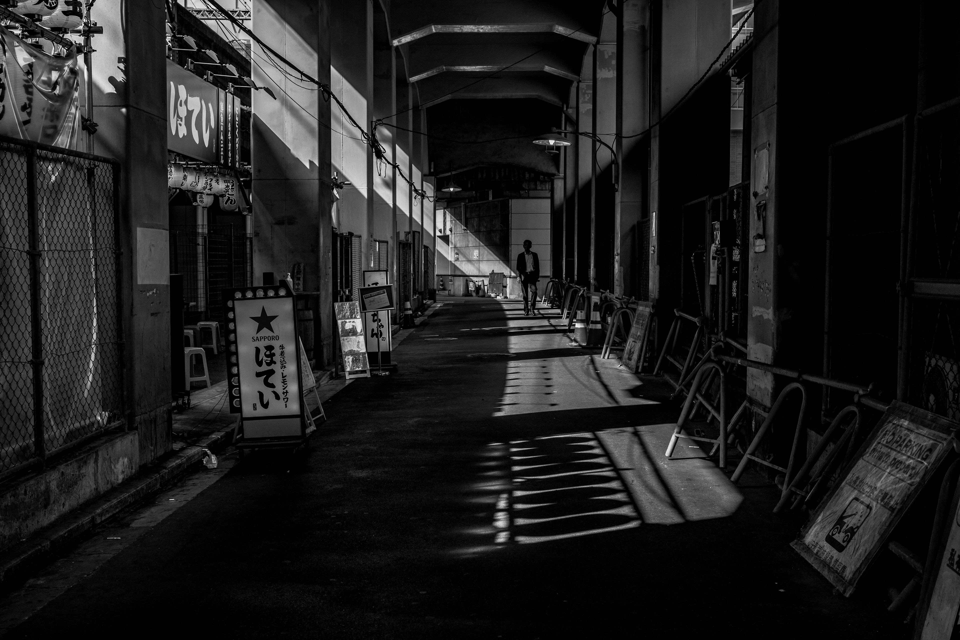 Foto in bianco e nero di un corridoio buio con forti contrasti di luce e ombra