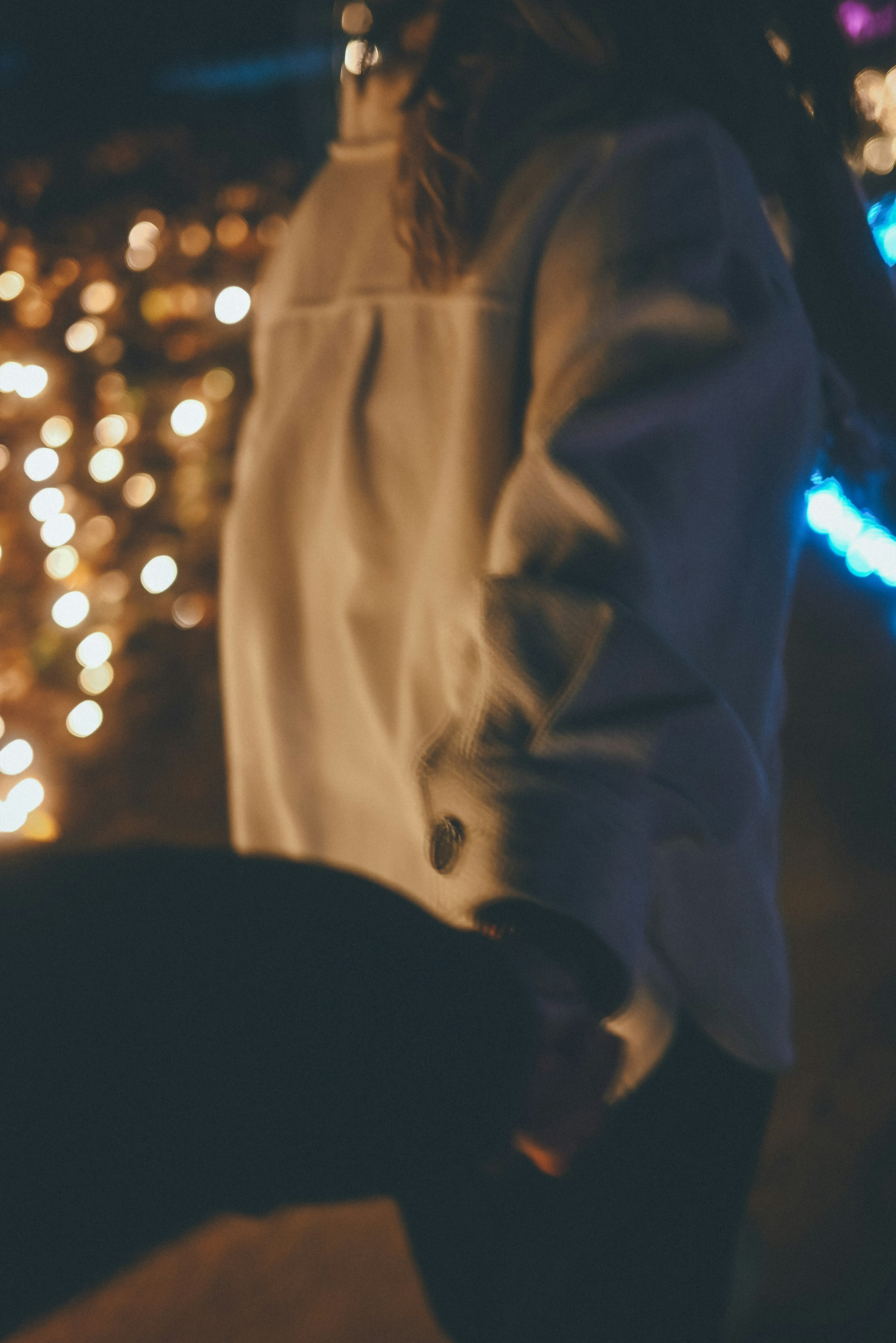 A person holding hands with another against a backdrop of decorative lights