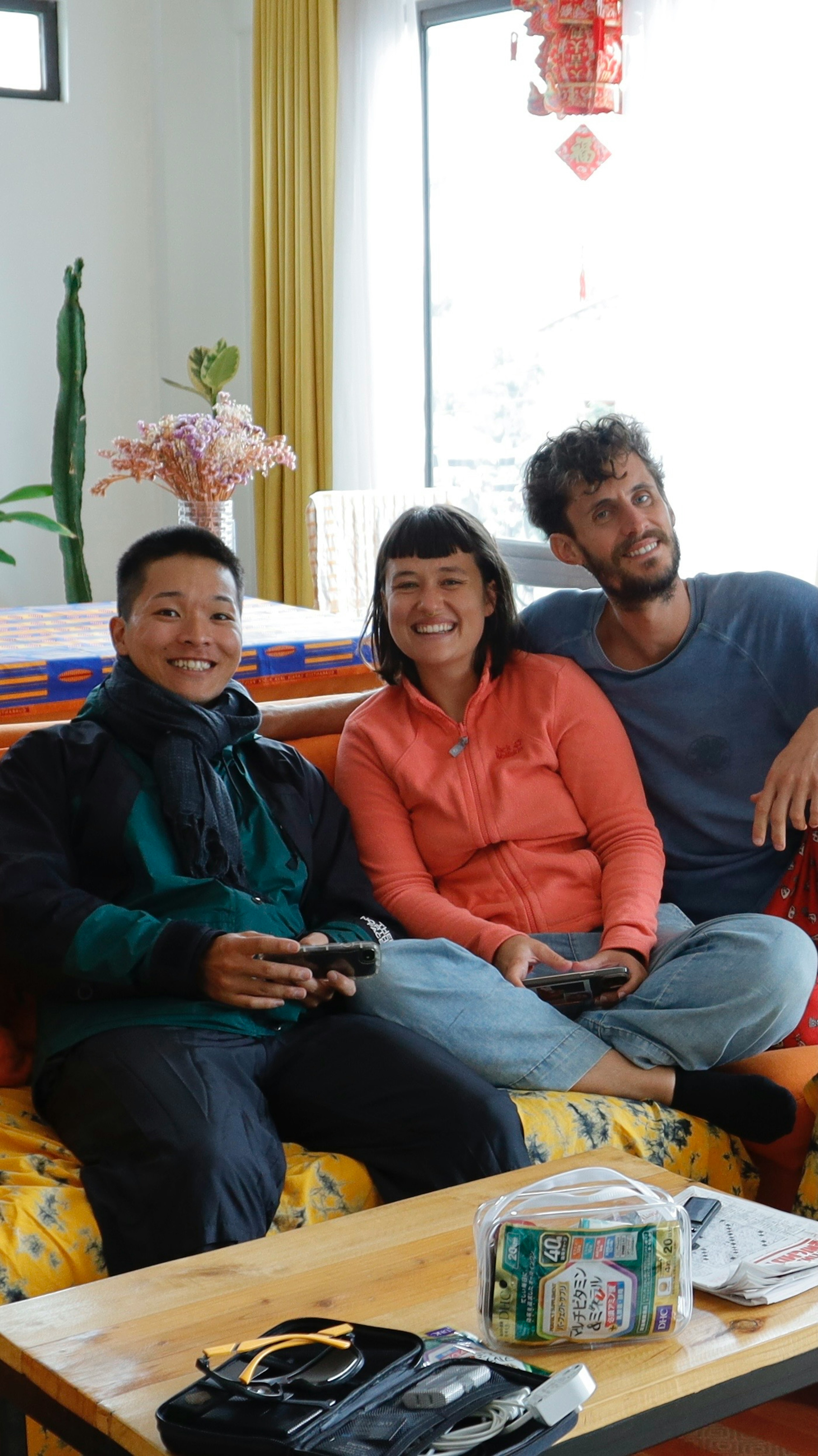 Trois amis assis sur un canapé coloré souriant dans un cadre intérieur confortable