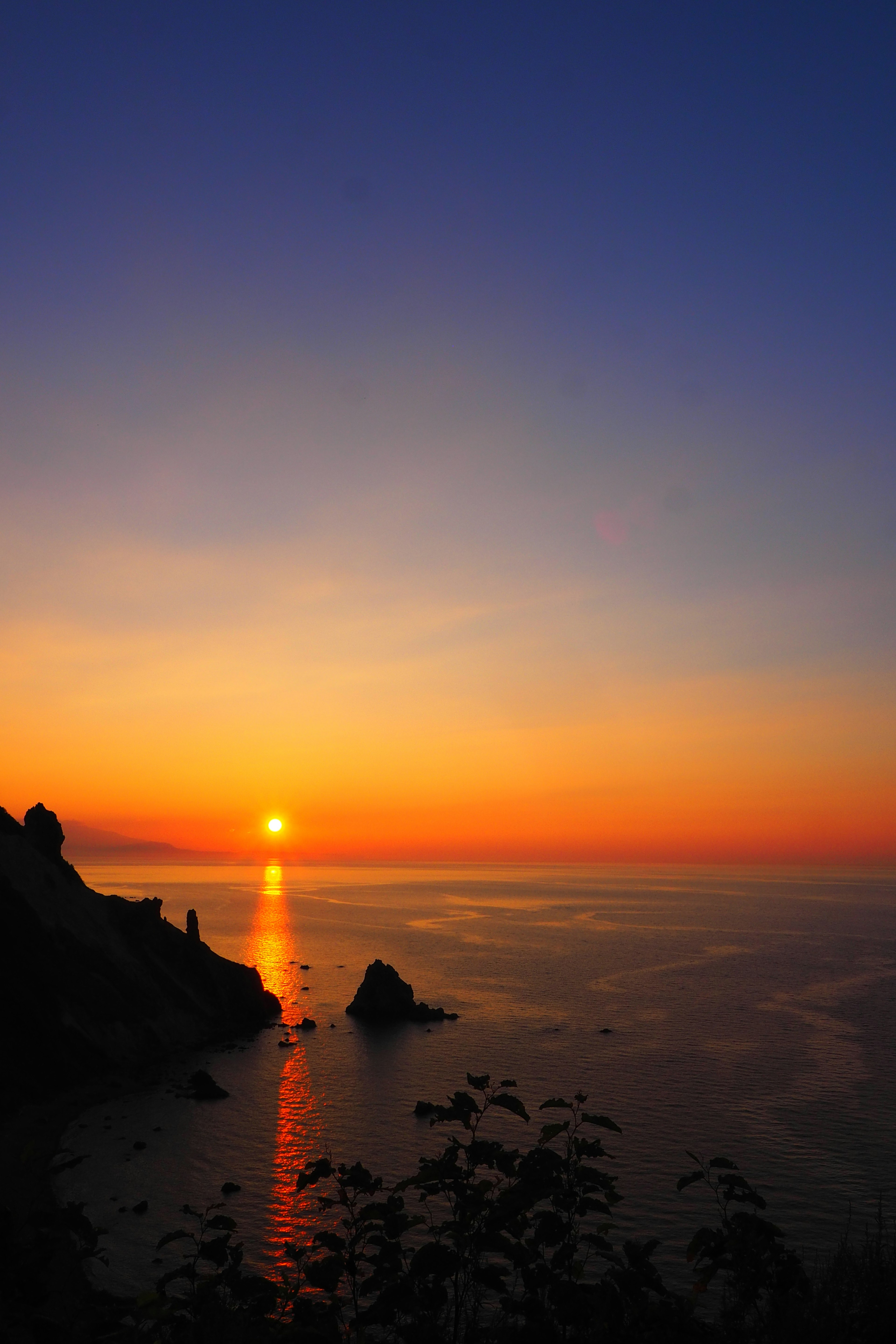 Beautiful sunset over the ocean with rocks and calm water