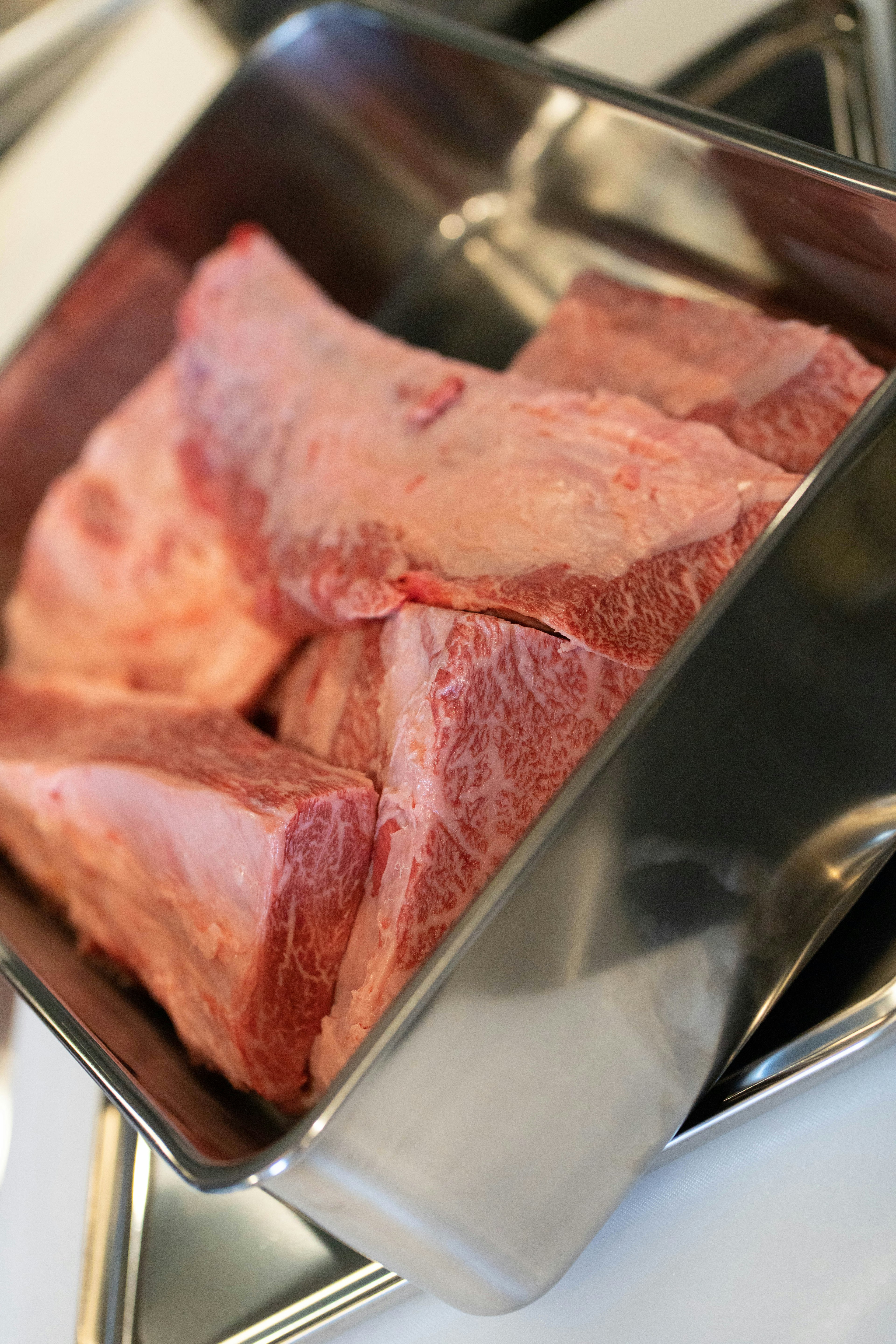 Piezas de carne cruda en una bandeja de acero inoxidable