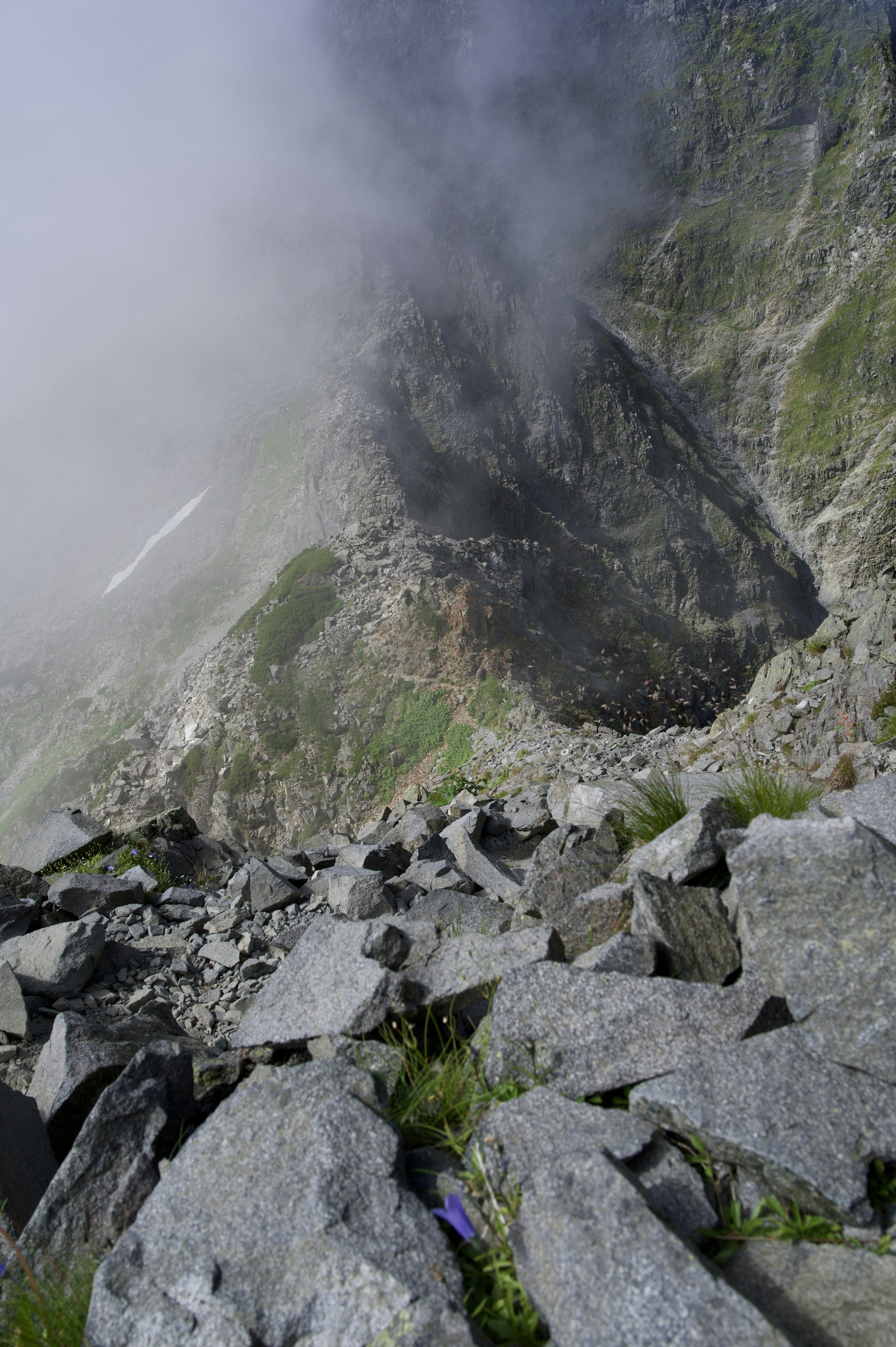 Mountain landscape shrouded in mist featuring rocky terrain and patches of grass