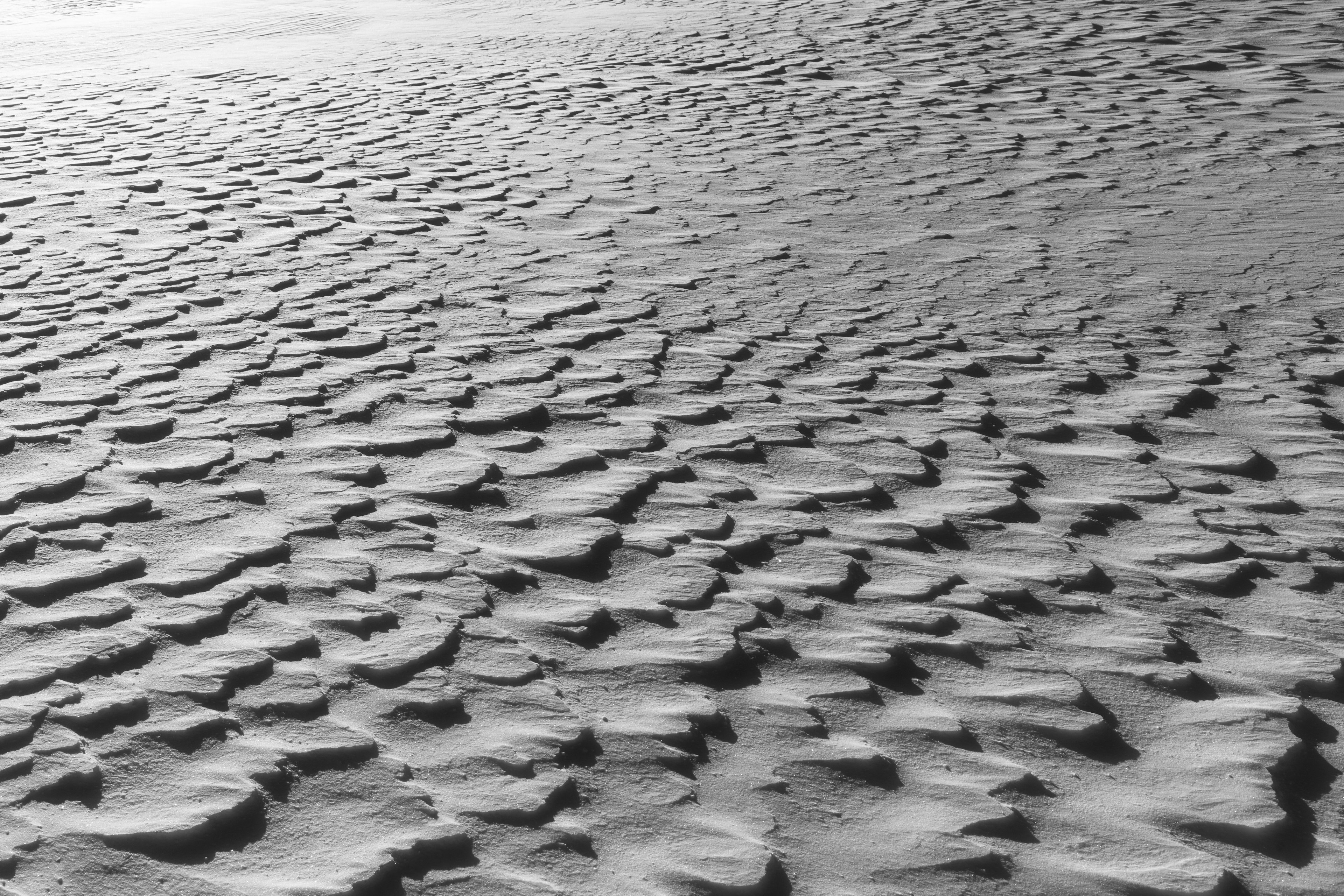 Superficie de arena en blanco y negro con patrones de dunas y sombras