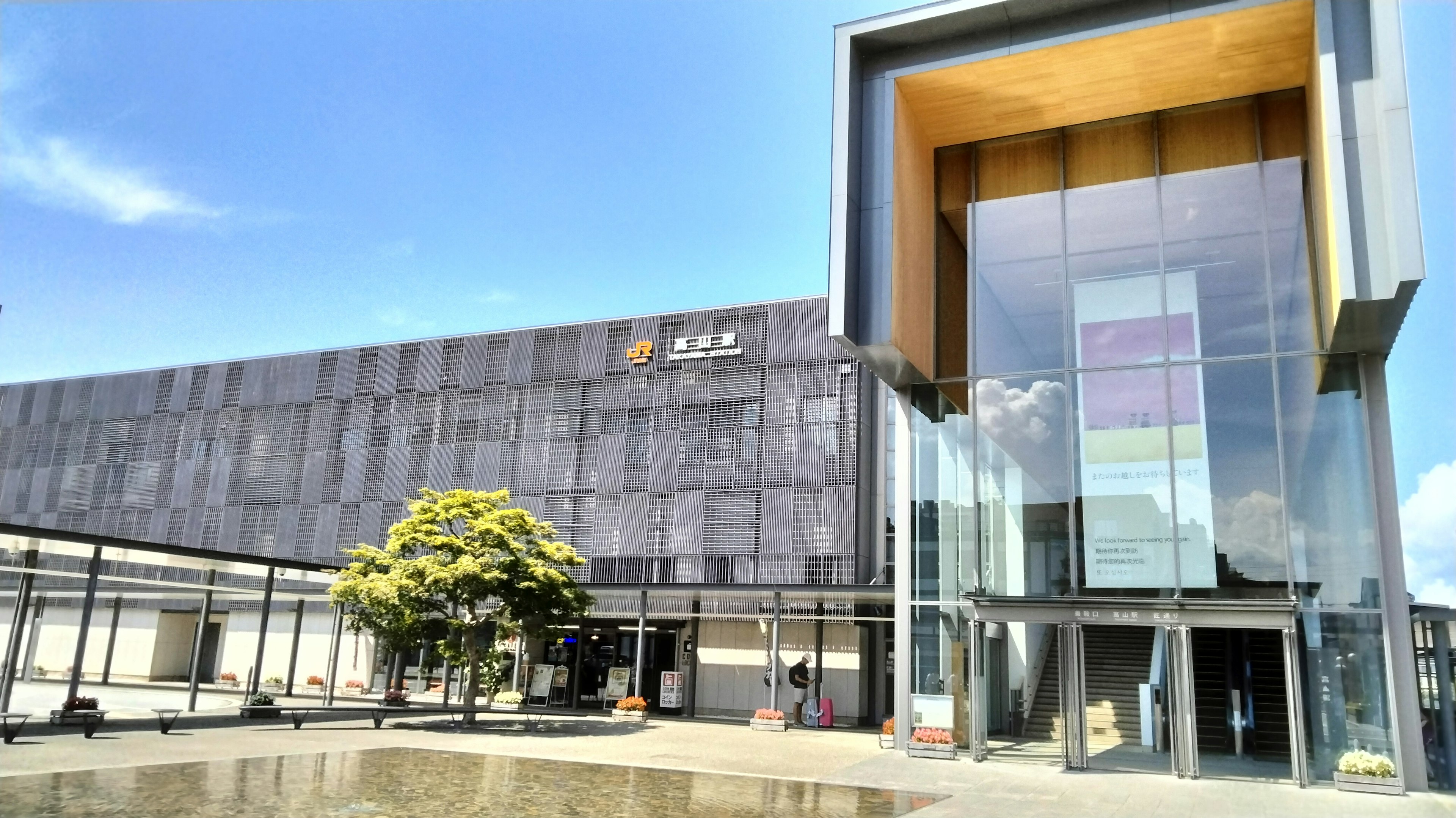 Modern building exterior with large glass entrance and green tree