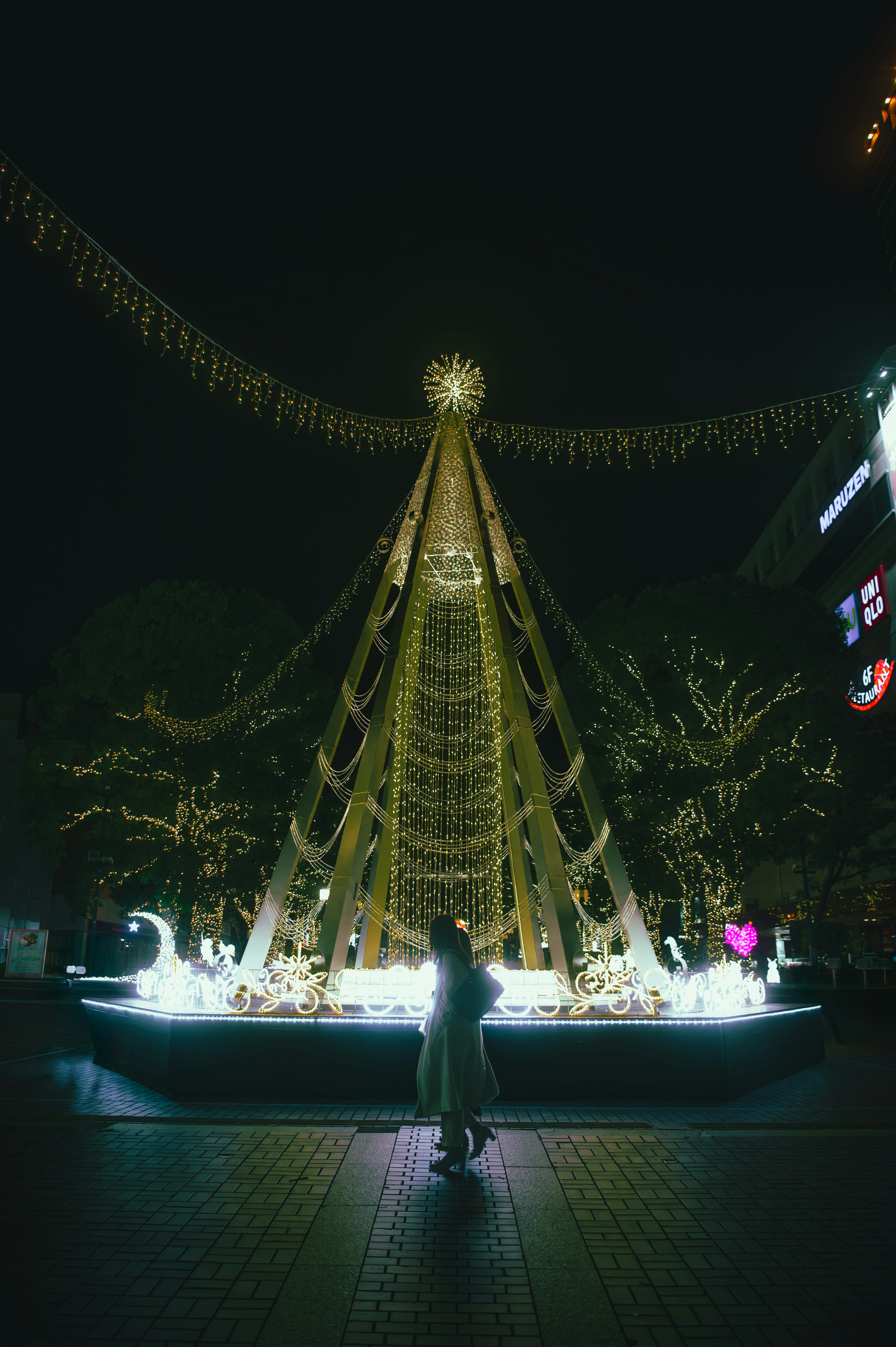 Pohon Natal yang diterangi di malam hari dengan lampu dekoratif