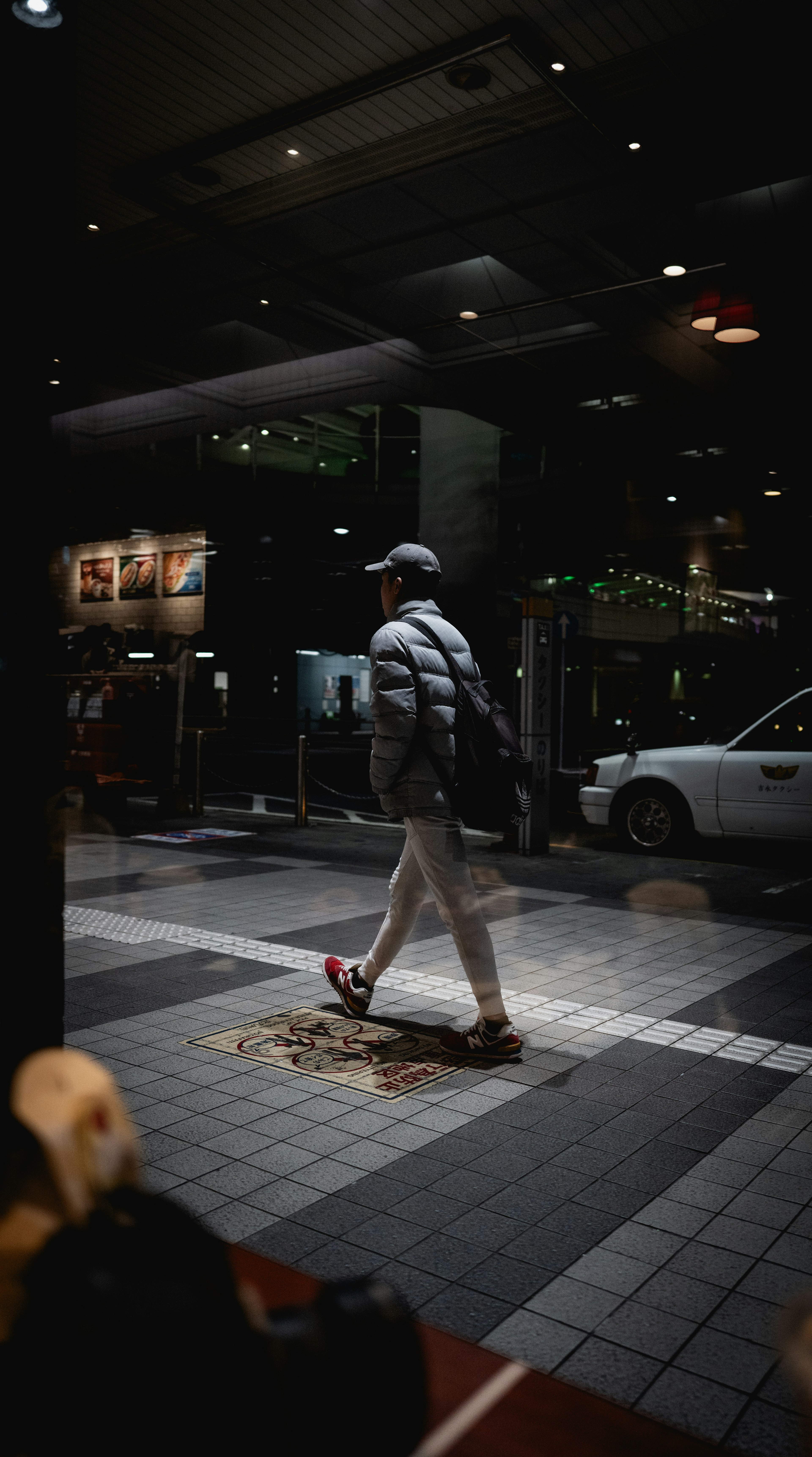 Siluet seorang pria berjalan di kota malam dengan lampu sekeliling