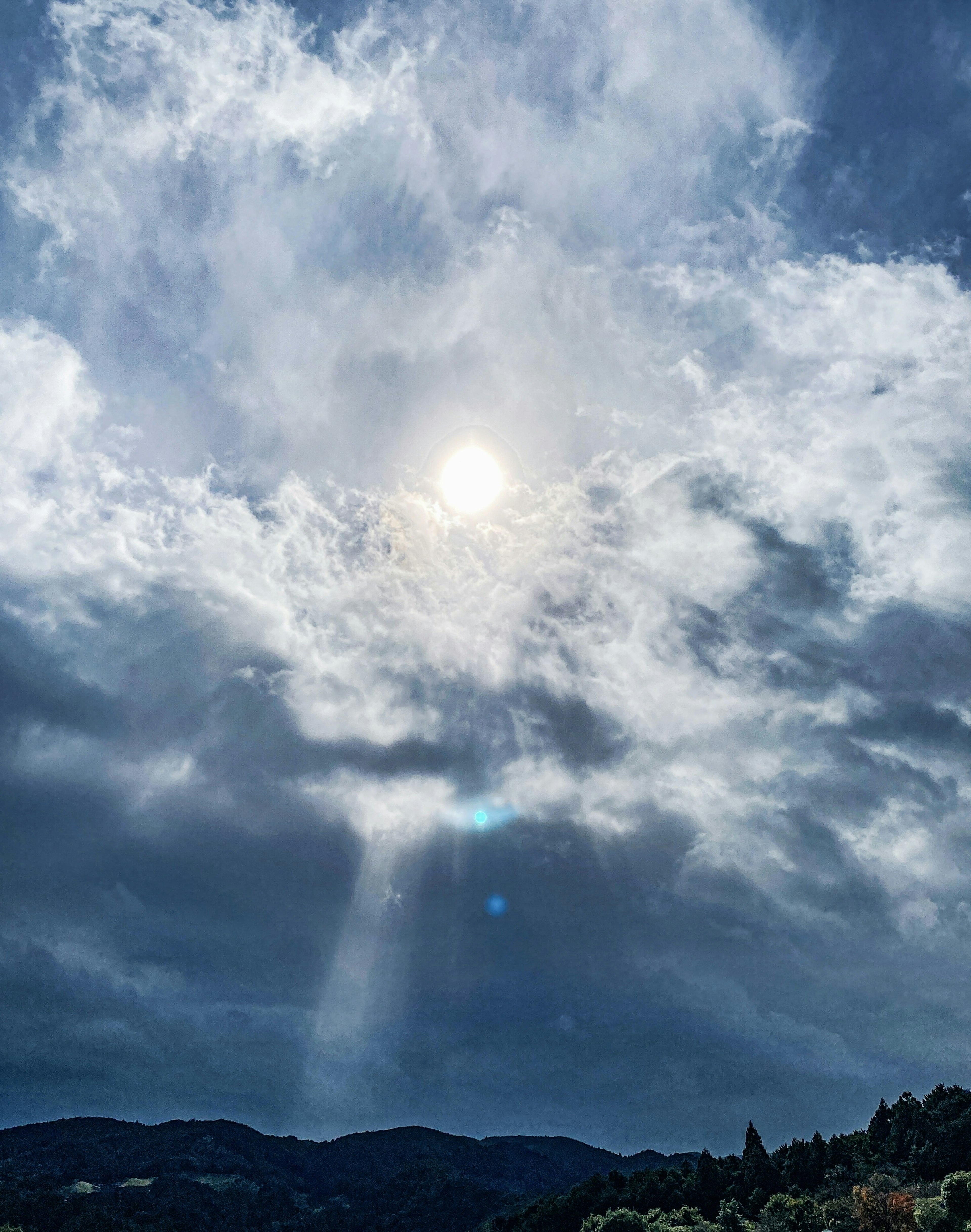 Sunlight breaking through clouds over a mountainous landscape