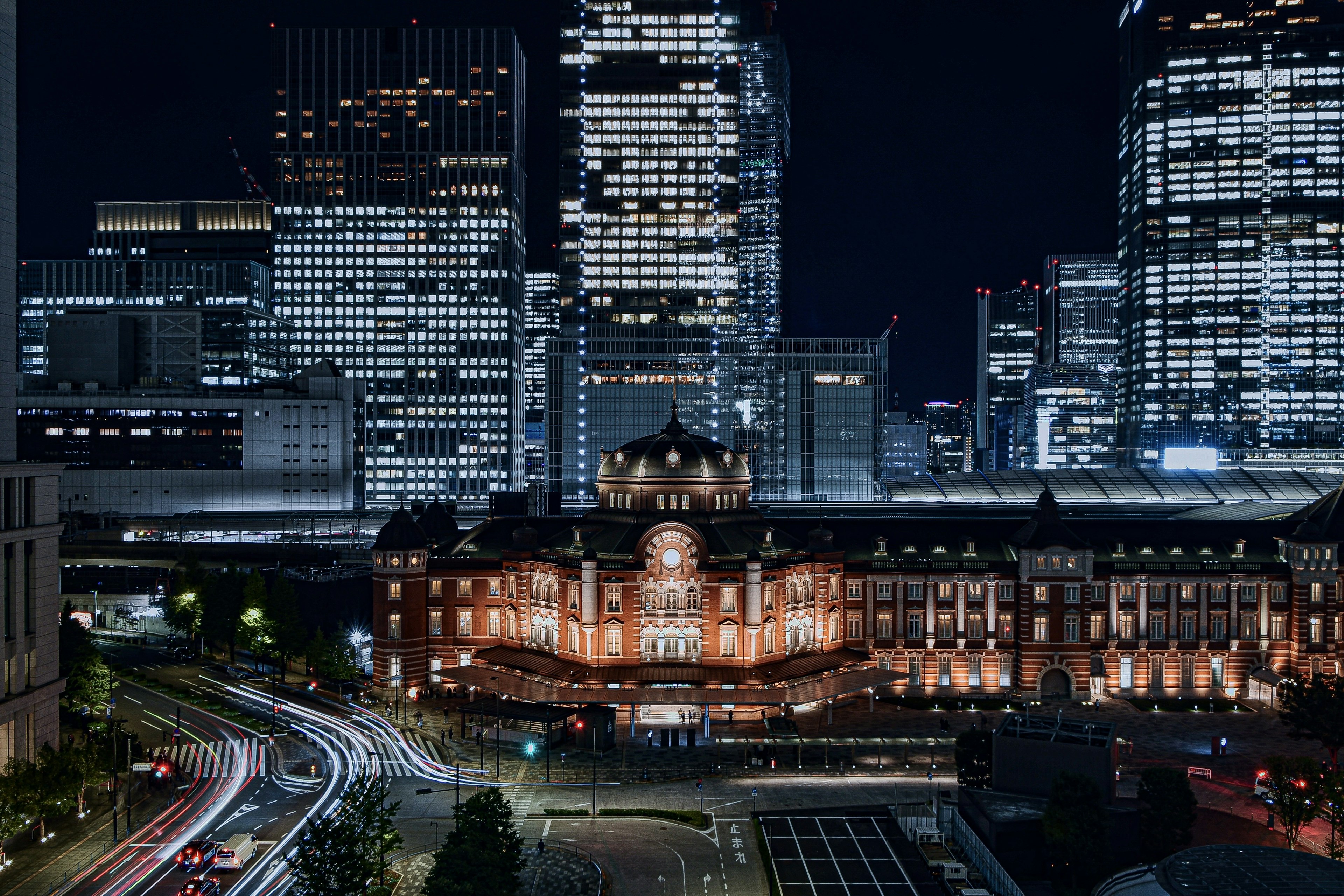 Estación de Tokio de noche con edificios iluminados y rascacielos