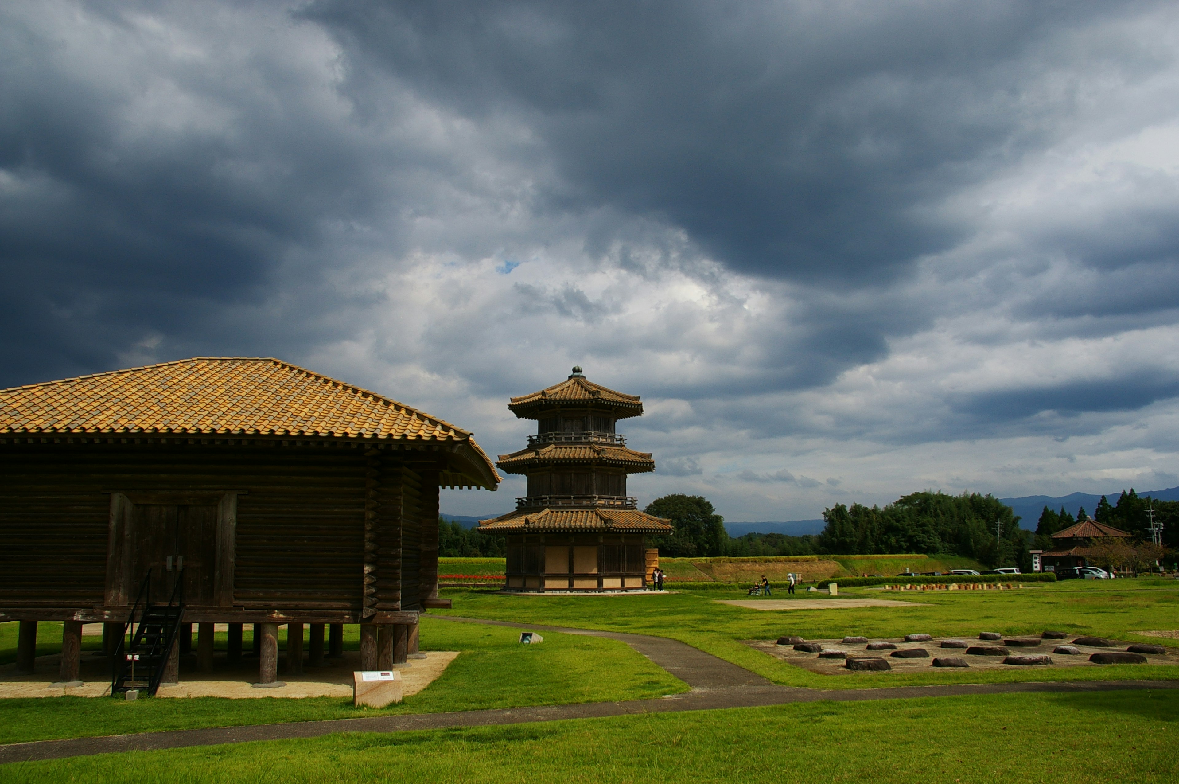 Traditionelle Gebäude und Pagode in einem grünen Feld unter einem bewölkten Himmel