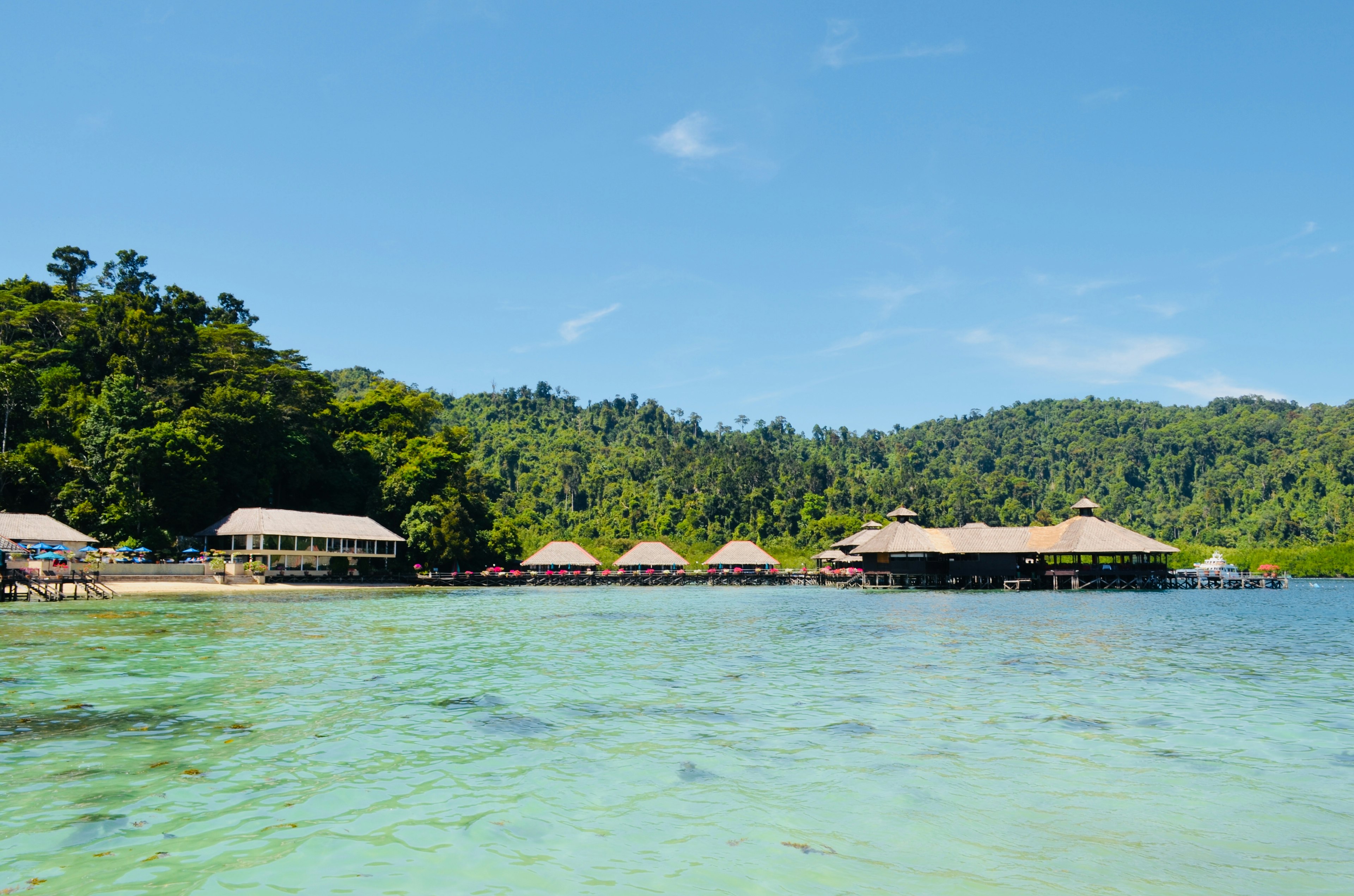 Scenic view of a resort surrounded by clear blue water and lush green hills