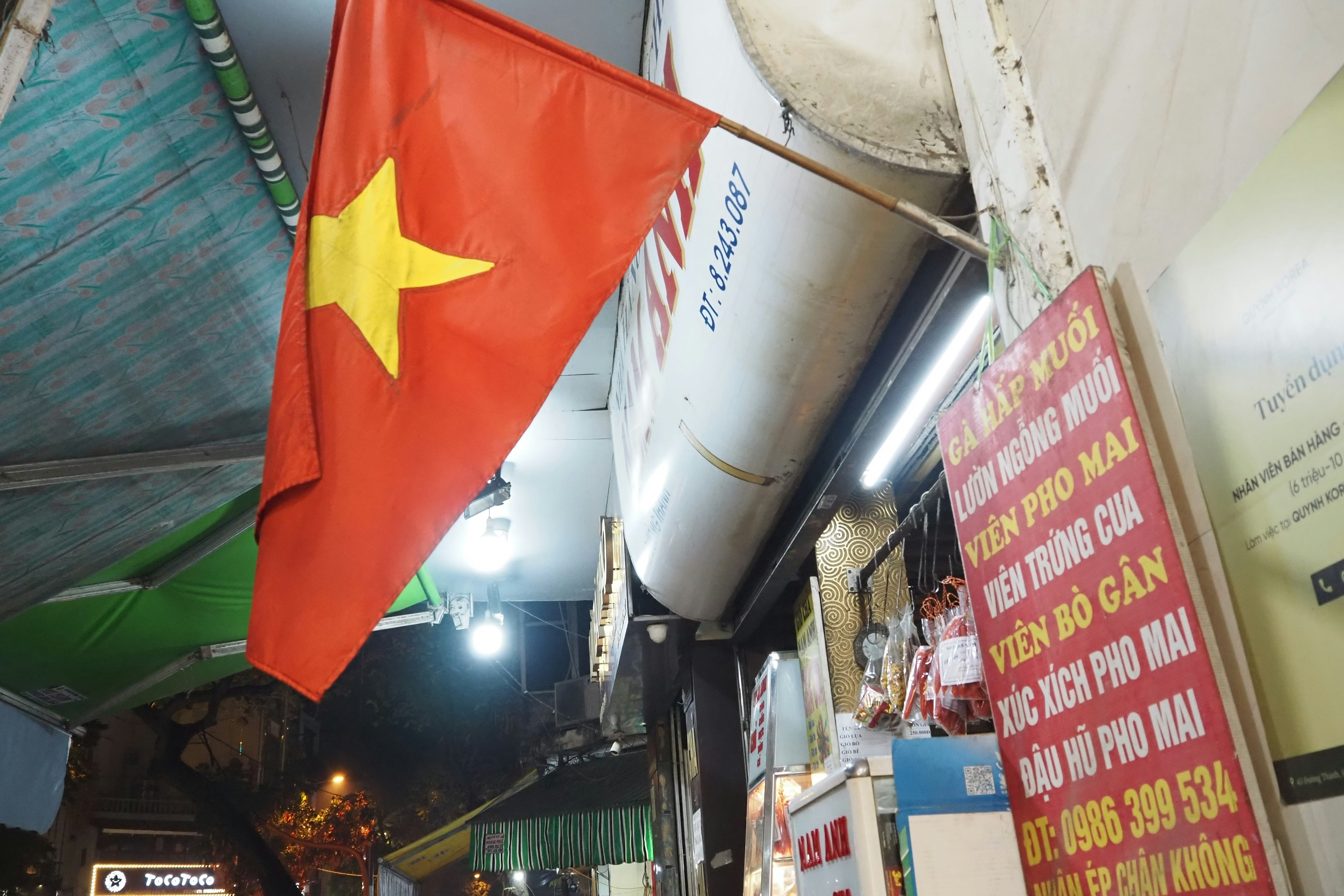 Bandera vietnamita colgando de un vendedor callejero por la noche