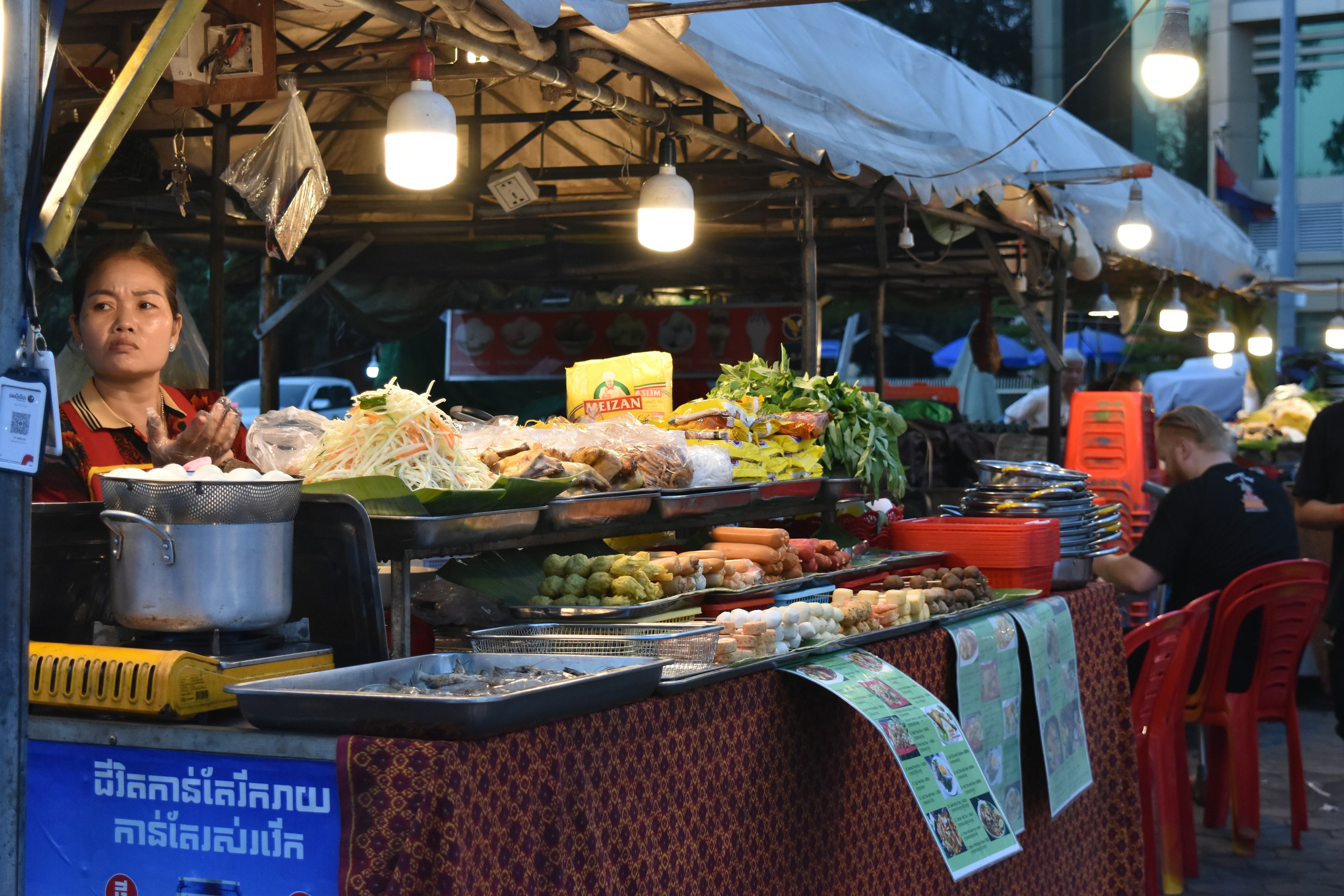 Frau verkauft frische Produkte auf einem Nachtmarkt lebendige Straßenessen-Szene