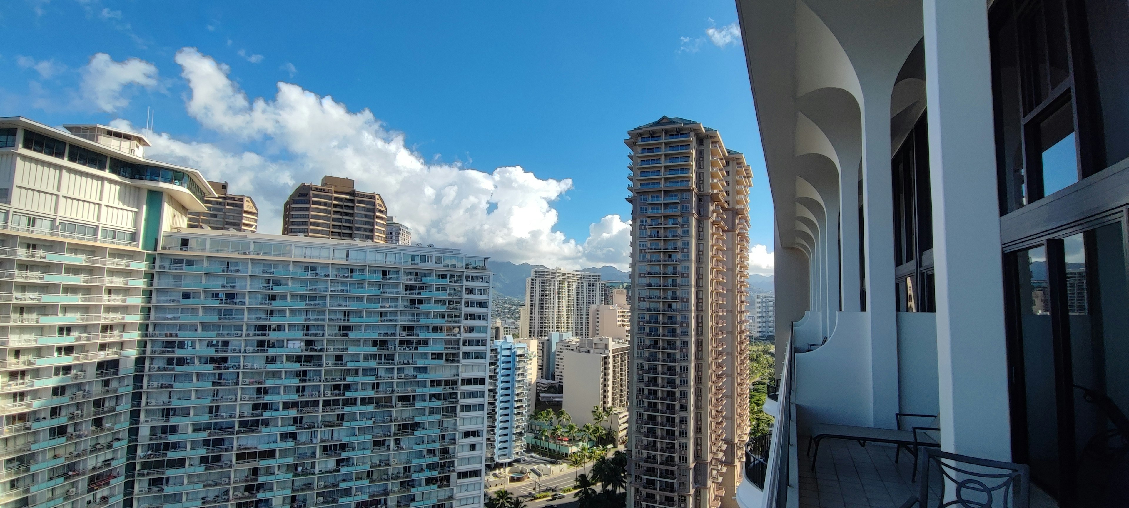 Vue depuis un balcon montrant des gratte-ciels sous un ciel bleu clair