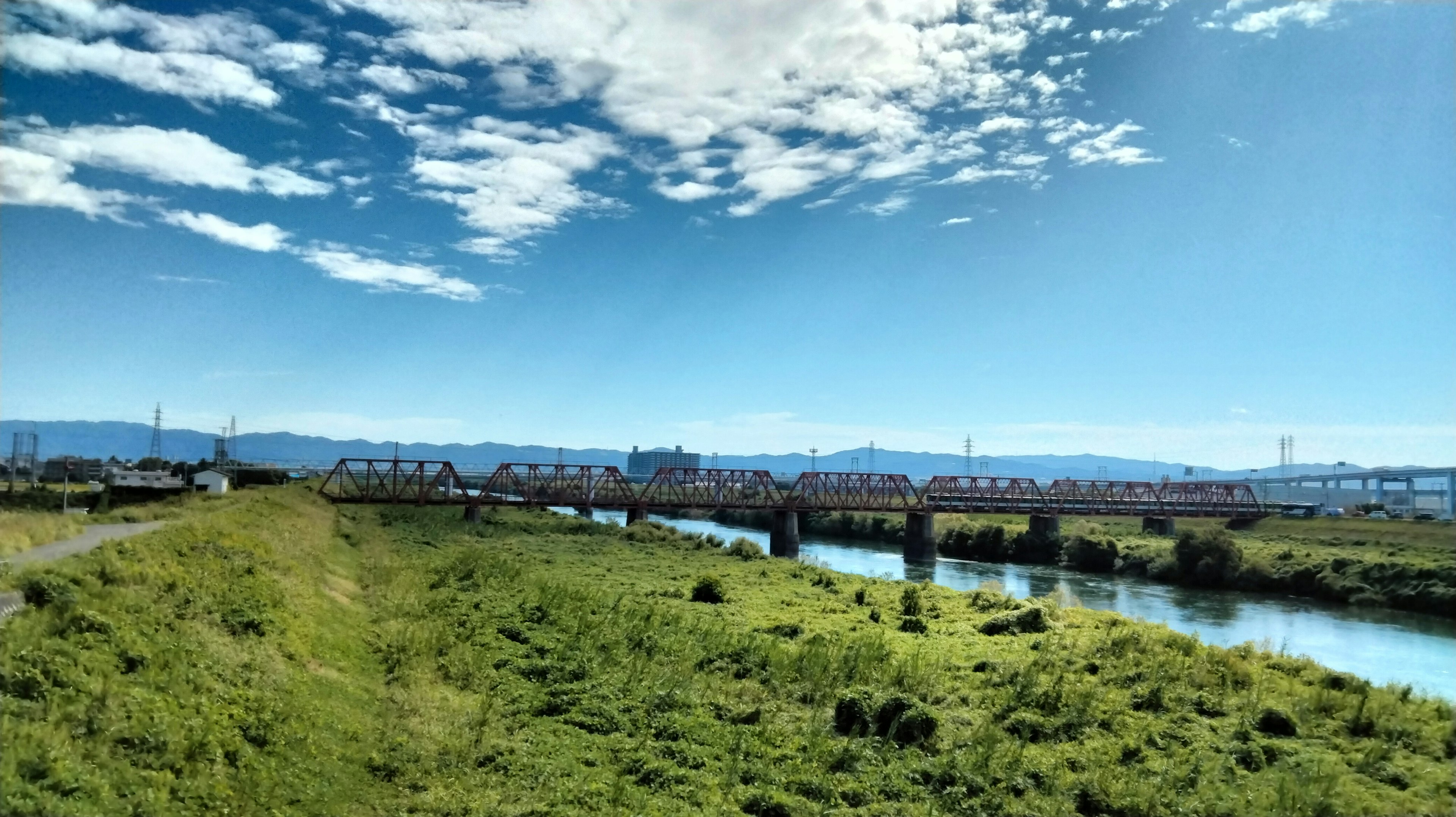 Eine malerische Aussicht mit klarem blauen Himmel und grünen Wiesen mit einem fließenden Fluss