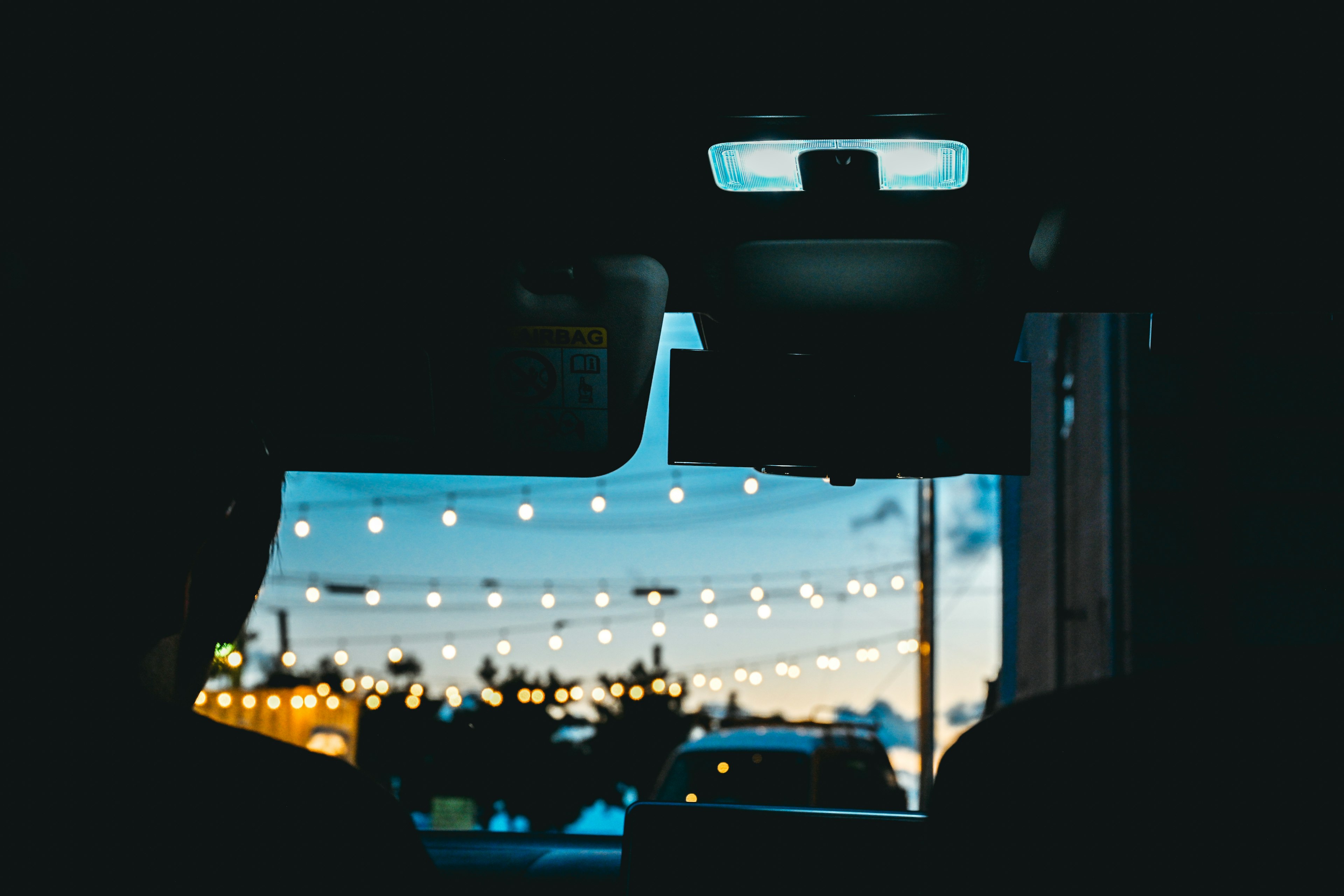 View from inside a car showcasing evening lights and a colorful sky