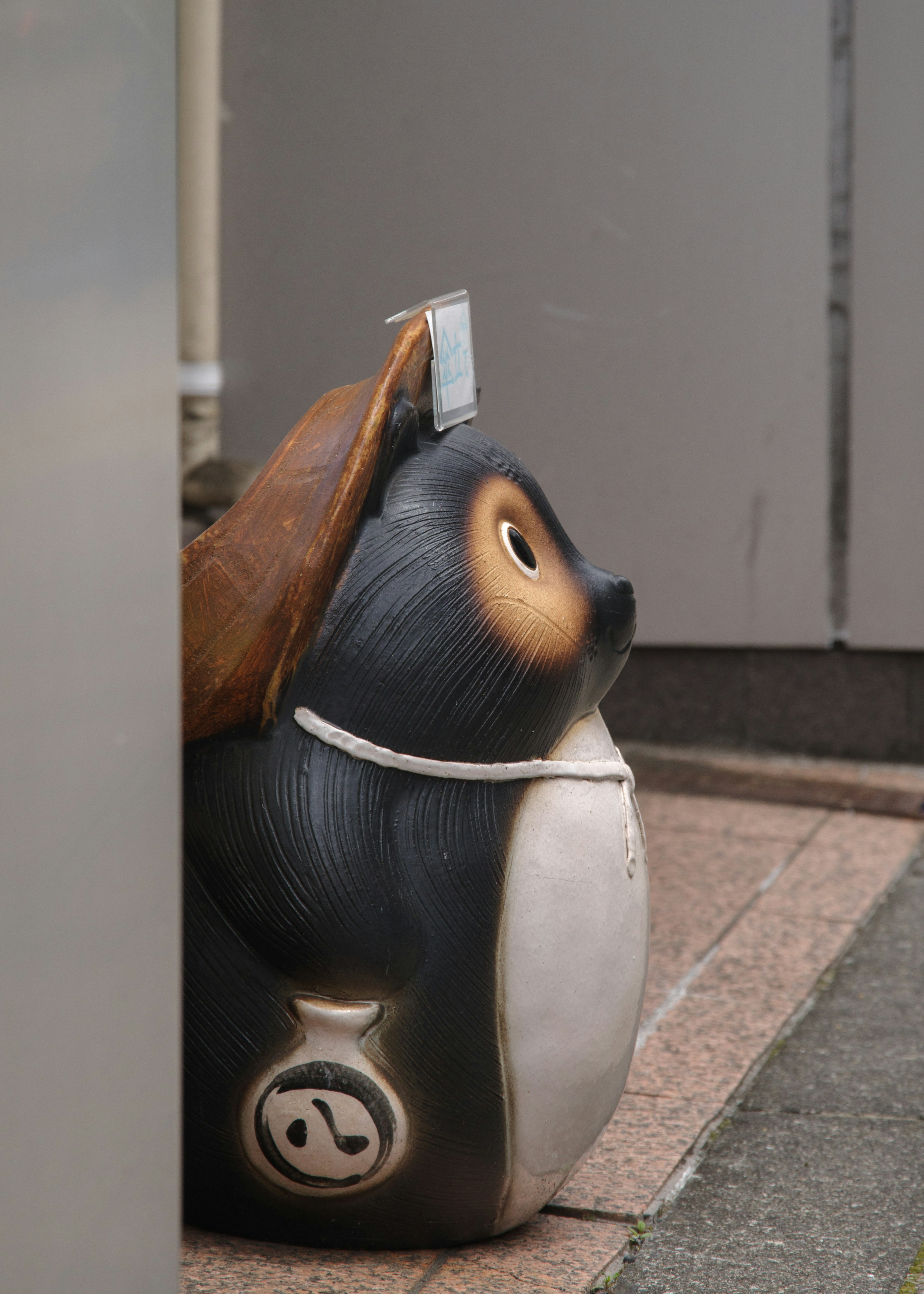 Una estatua de mapache negro colocada junto a una pared