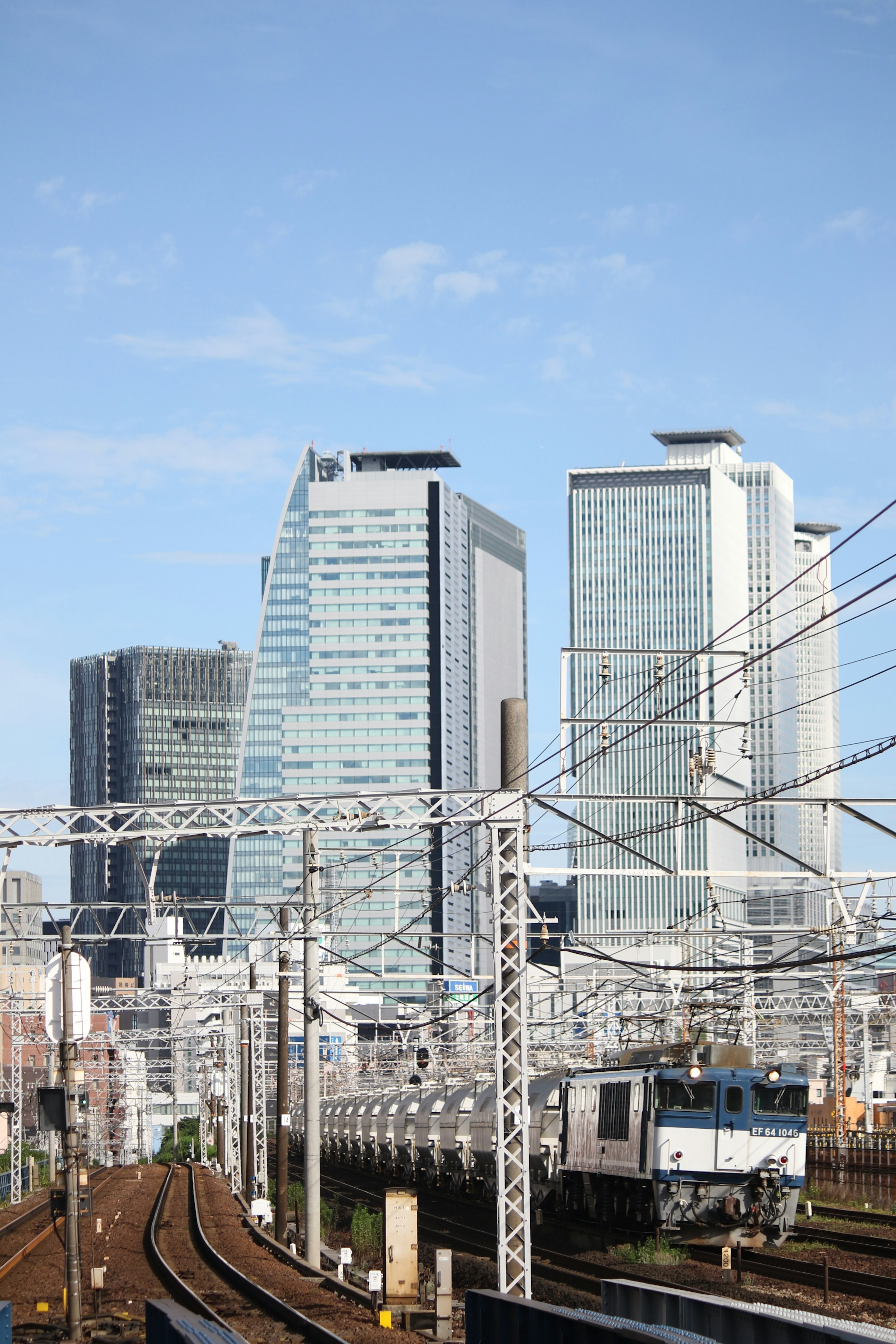 Skyline urbana con grattacieli moderni e binari ferroviari sotto un cielo blu