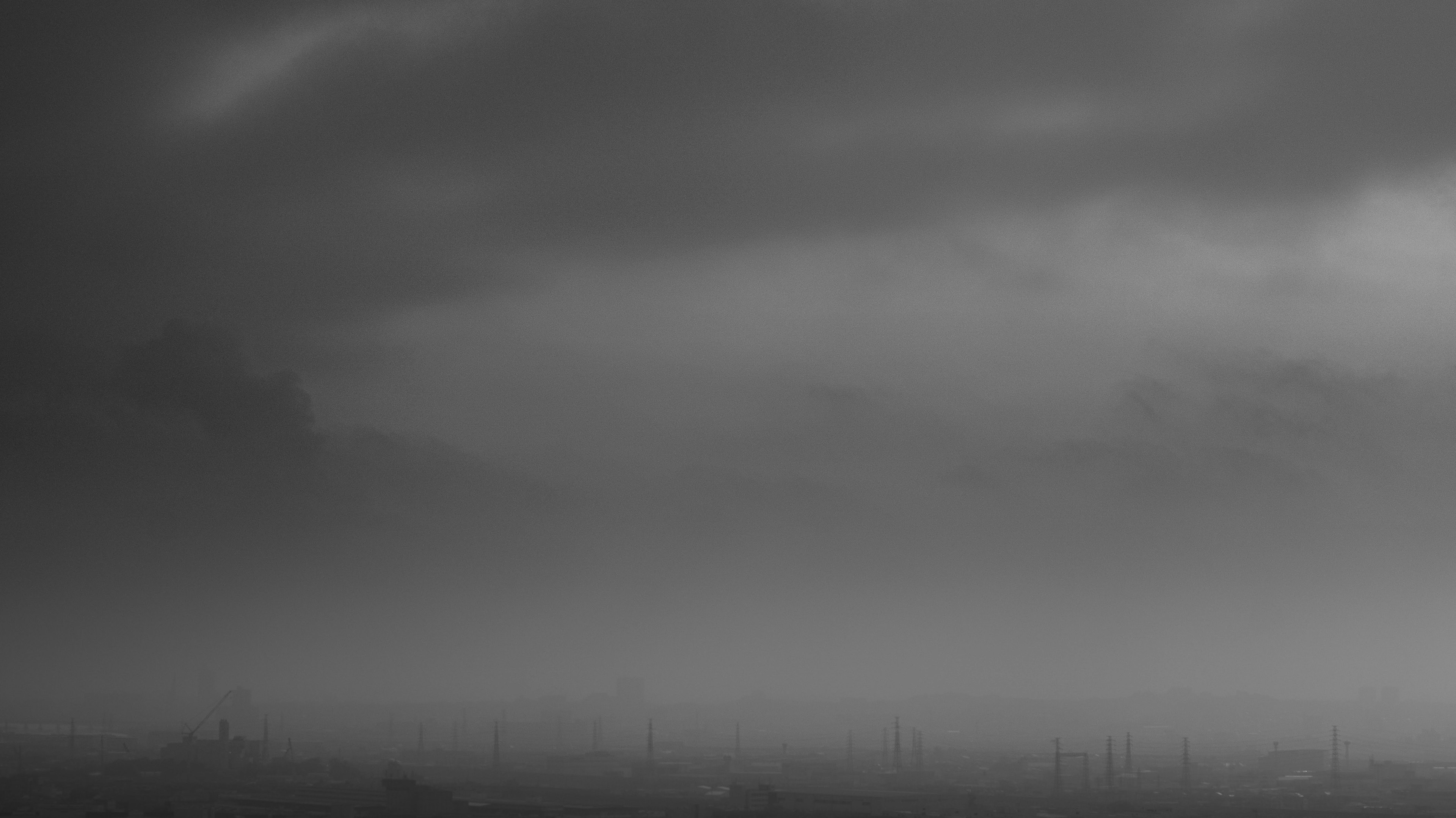 Paisaje en blanco y negro con nubes y siluetas distantes