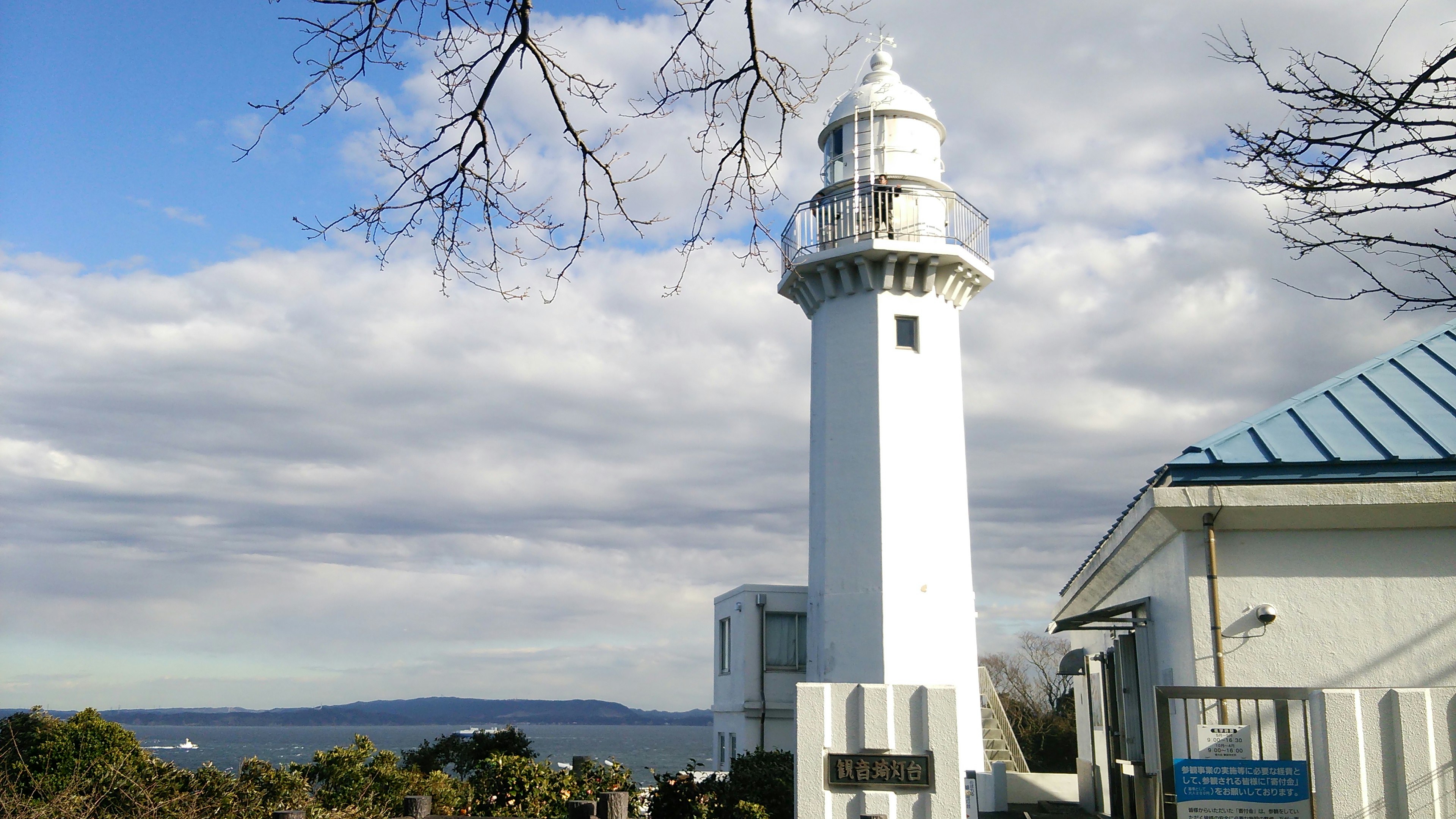 Faro bianco contro un cielo blu con nuvole