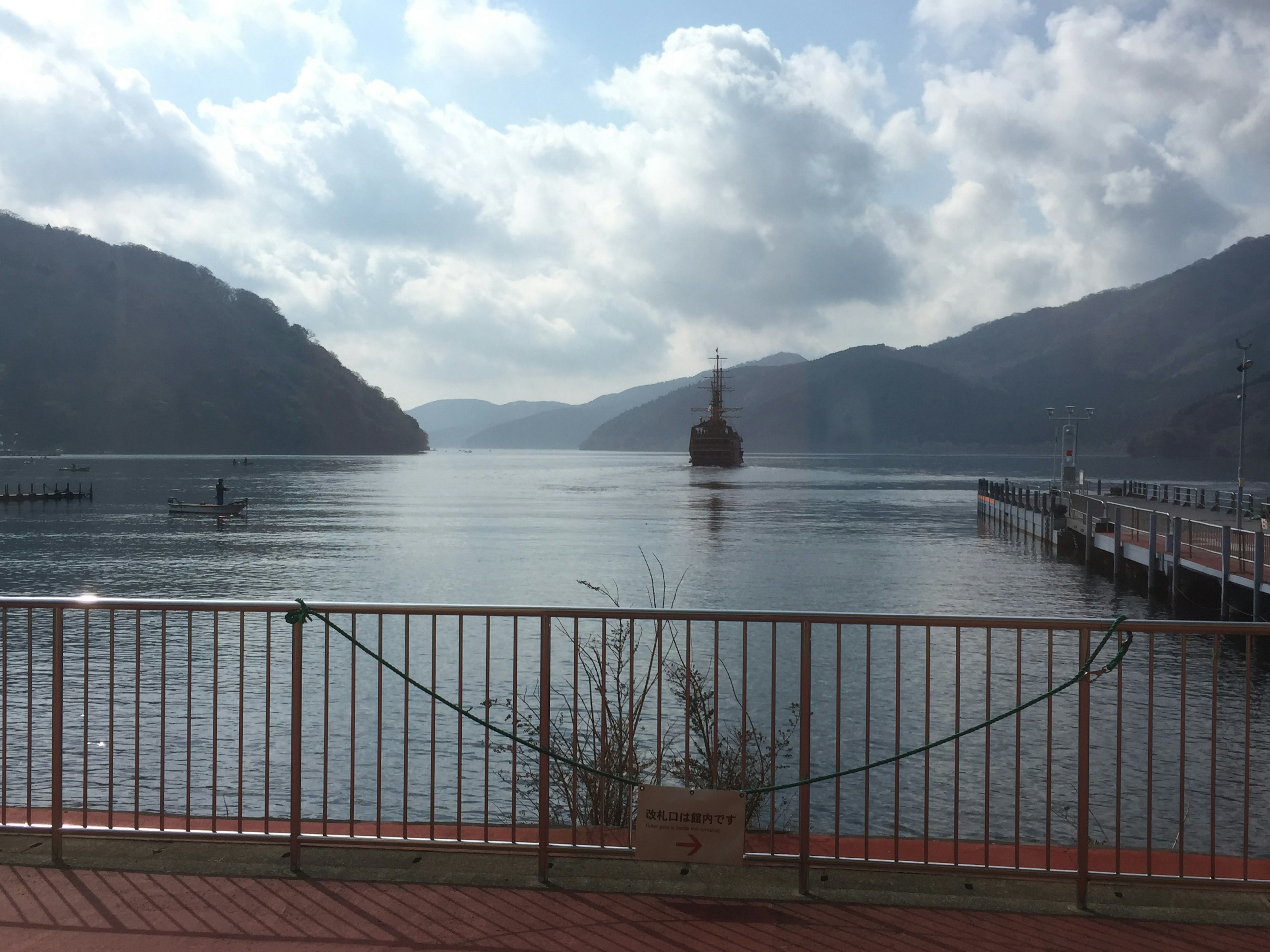 Ruhiger Blick auf den See umgeben von Bergen mit einem Boot in der Ferne