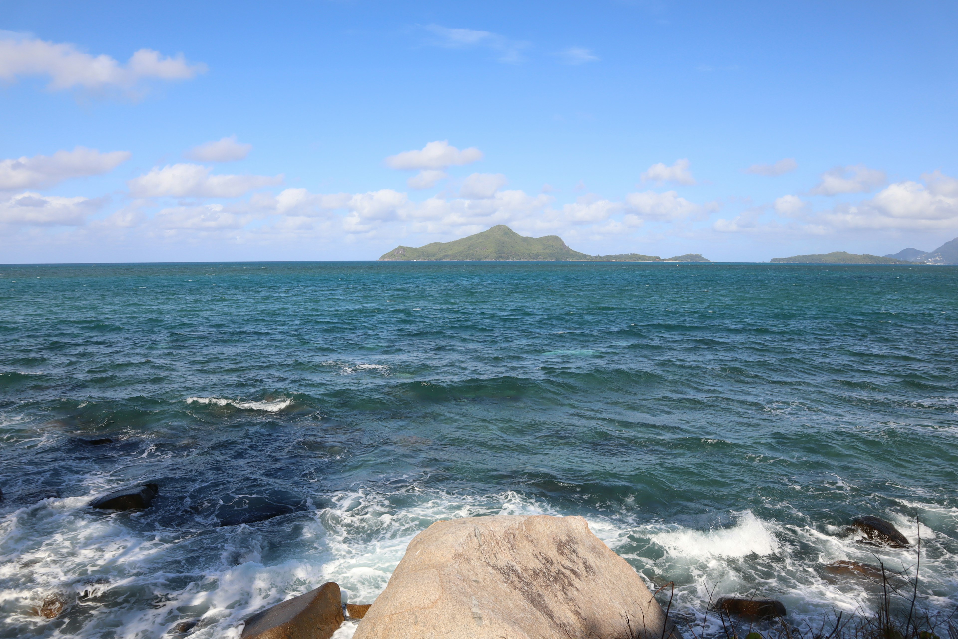 Küstenansicht mit blauem Meer und entfernter Insel