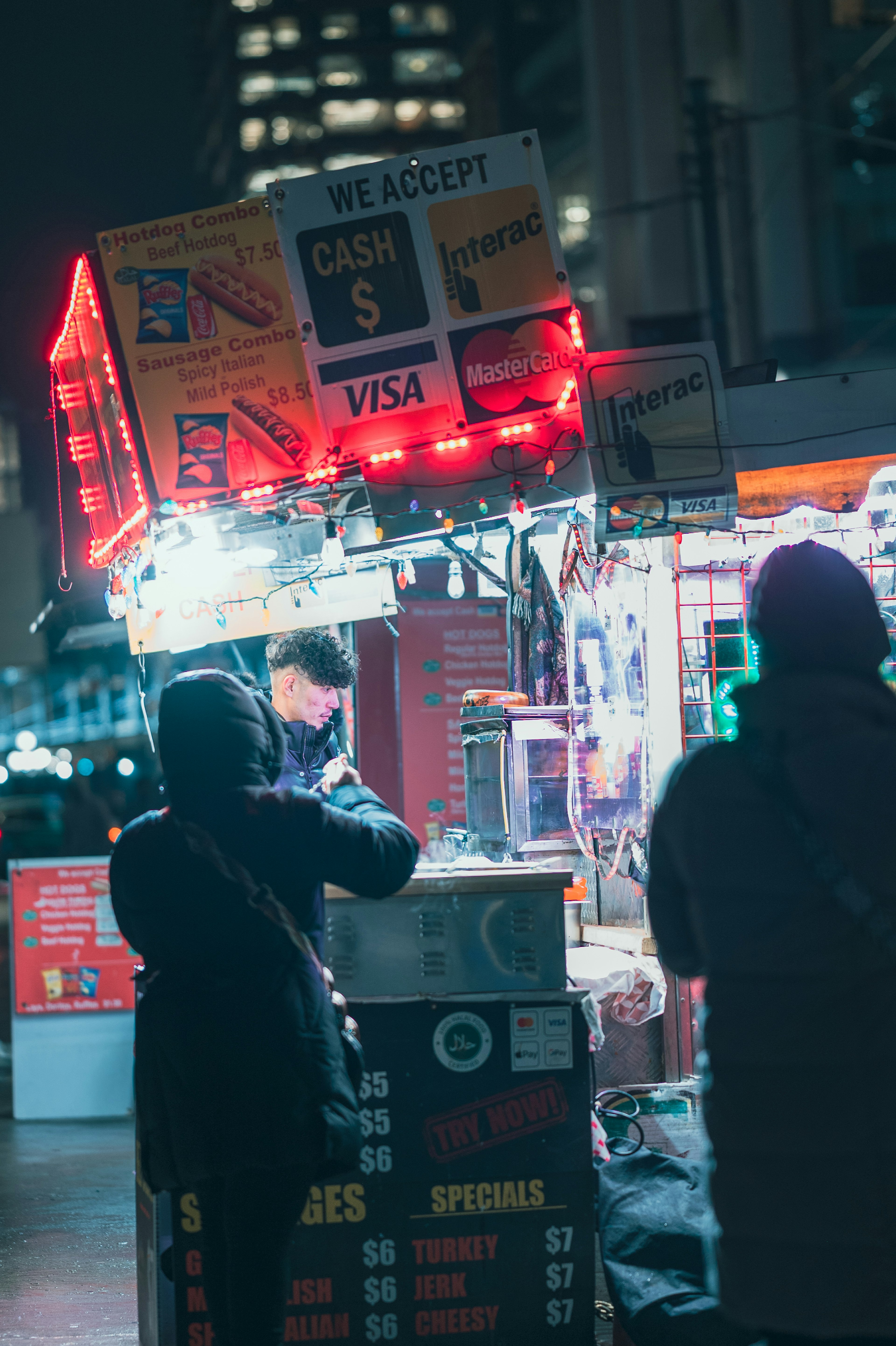 夜の屋台で食べ物を購入する人々と明るい看板