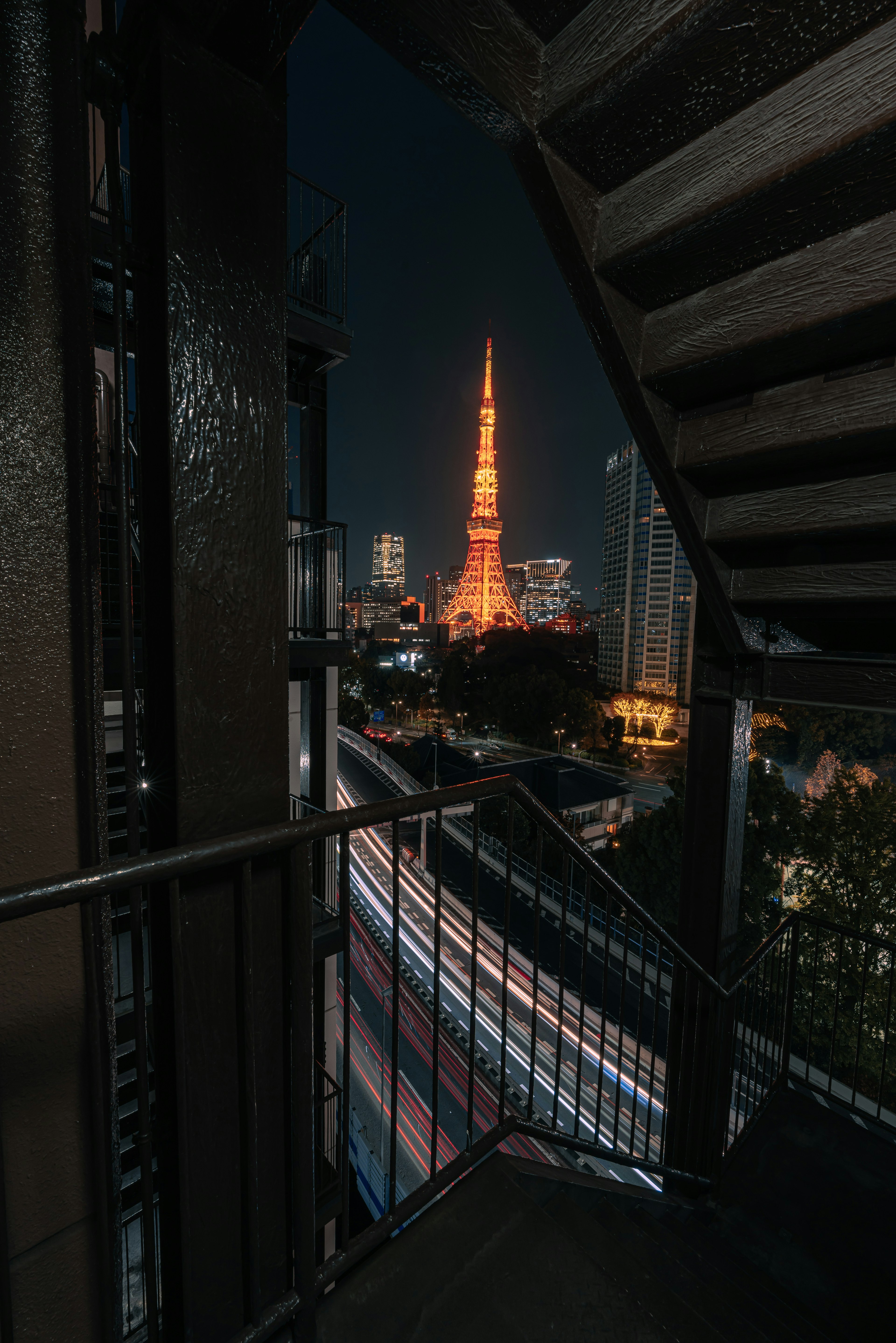 View of Tokyo Tower illuminated at night from a metal staircase