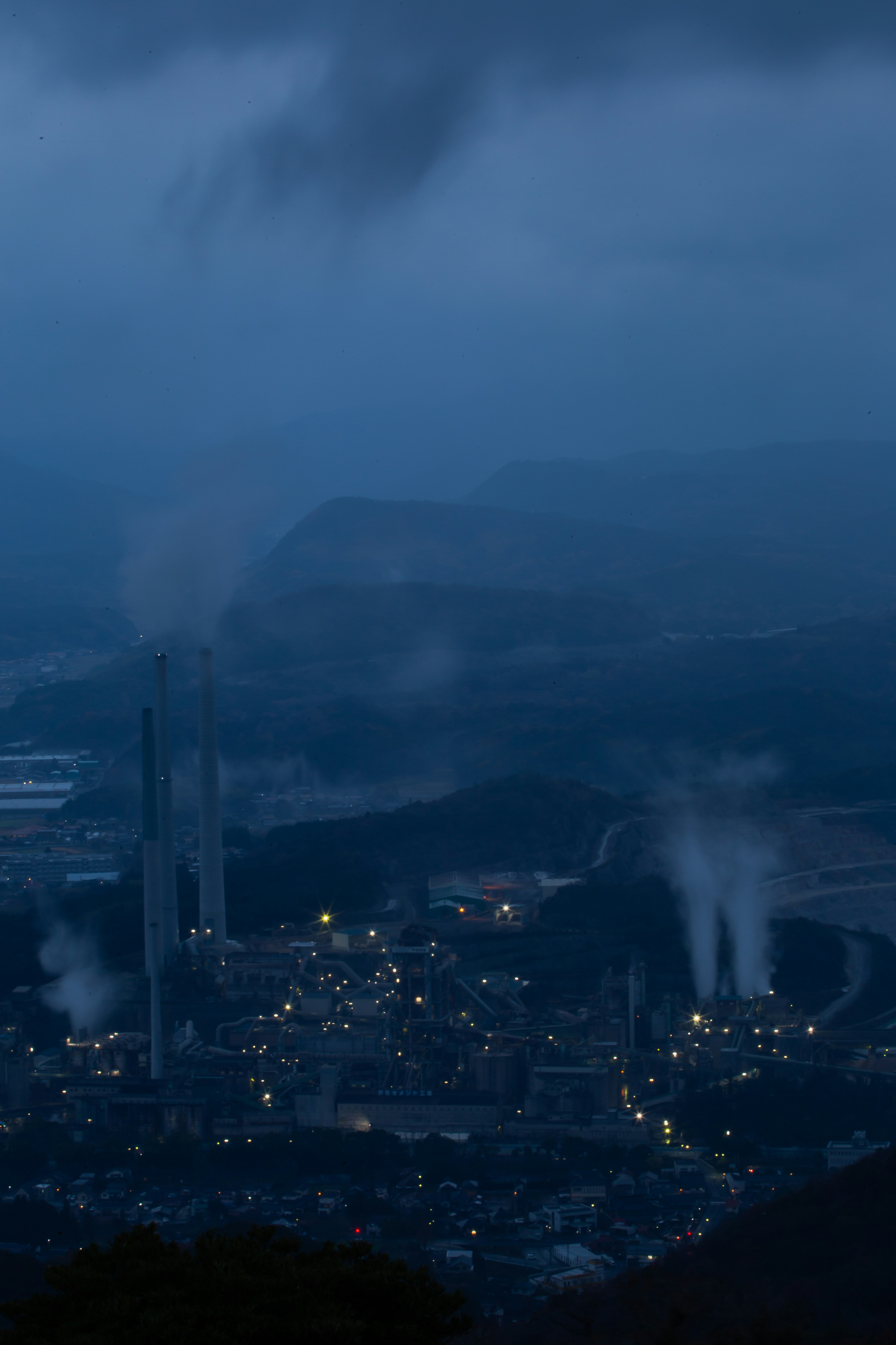 Industrial landscape with smokestacks emitting steam under a dark sky