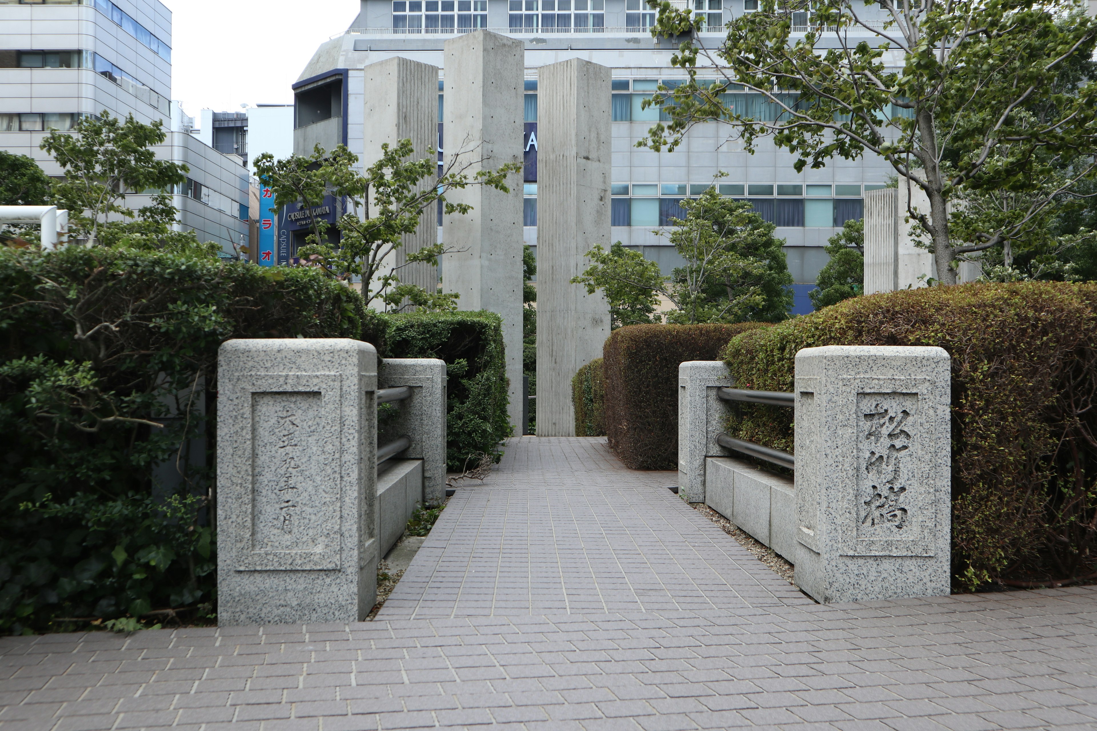 Stone bridge leading into a green pathway surrounded by bushes