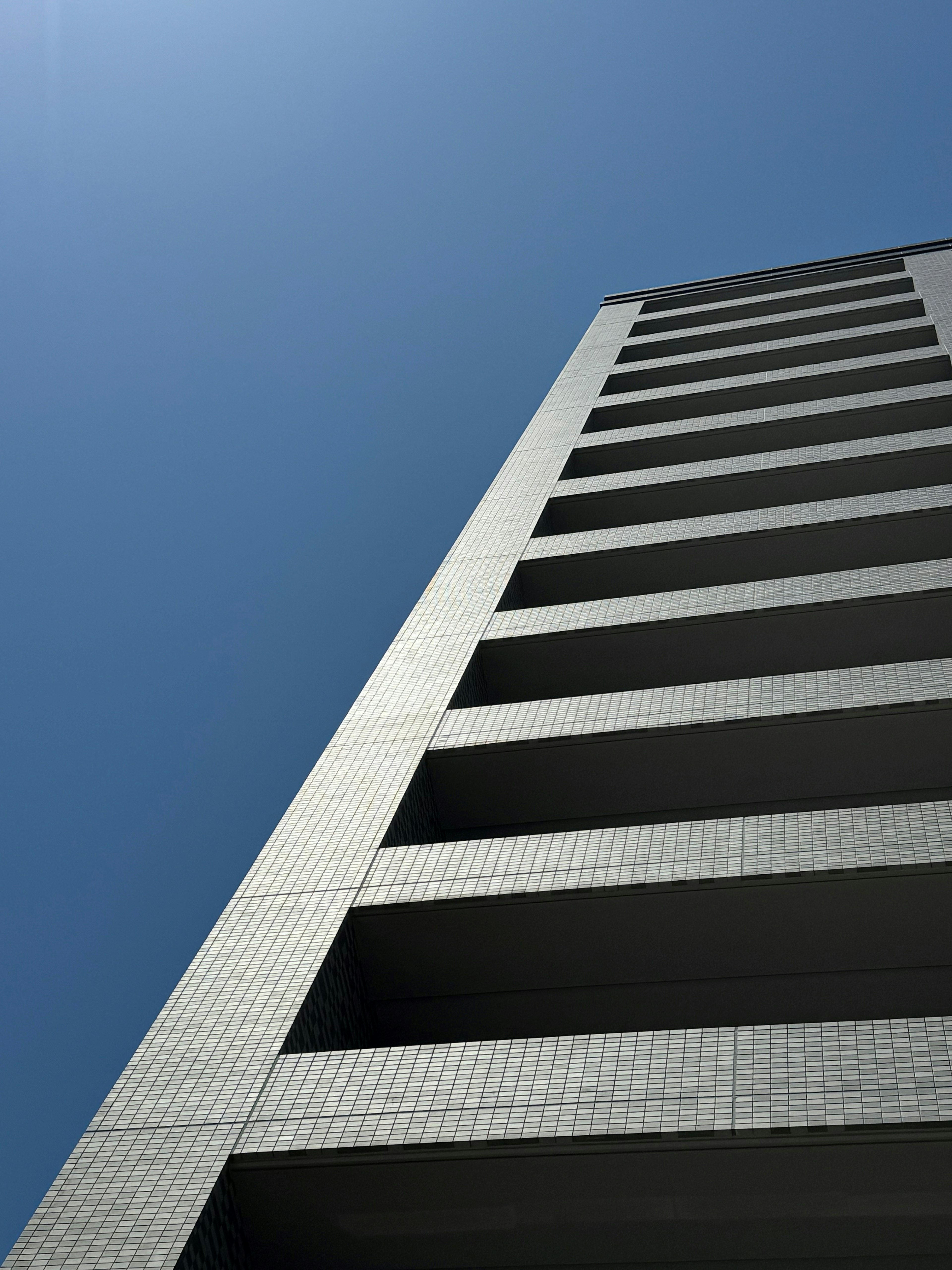 Foto eines Hochhauses von unten gegen einen klaren blauen Himmel