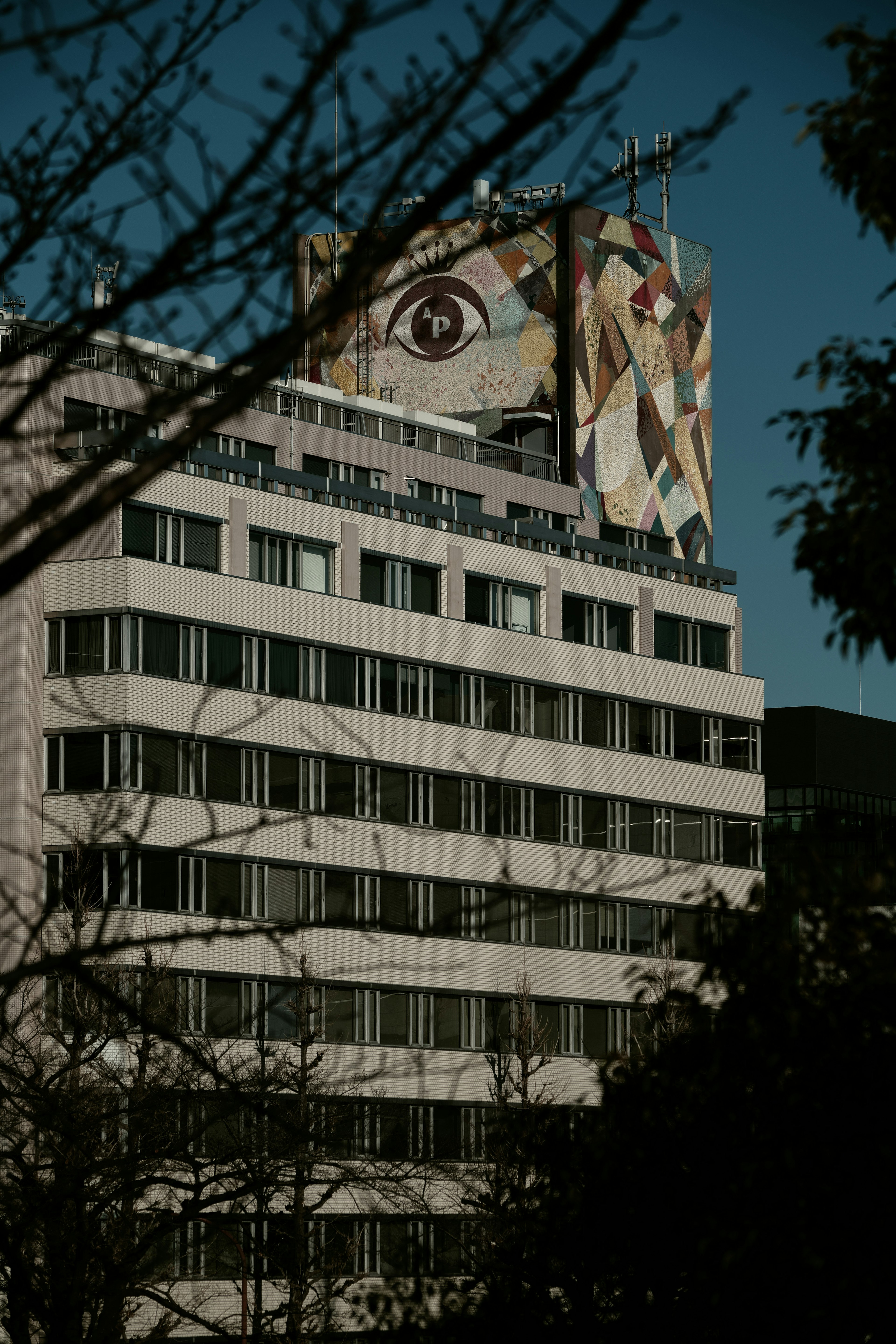 Edificio con mural de ojo y árboles circundantes