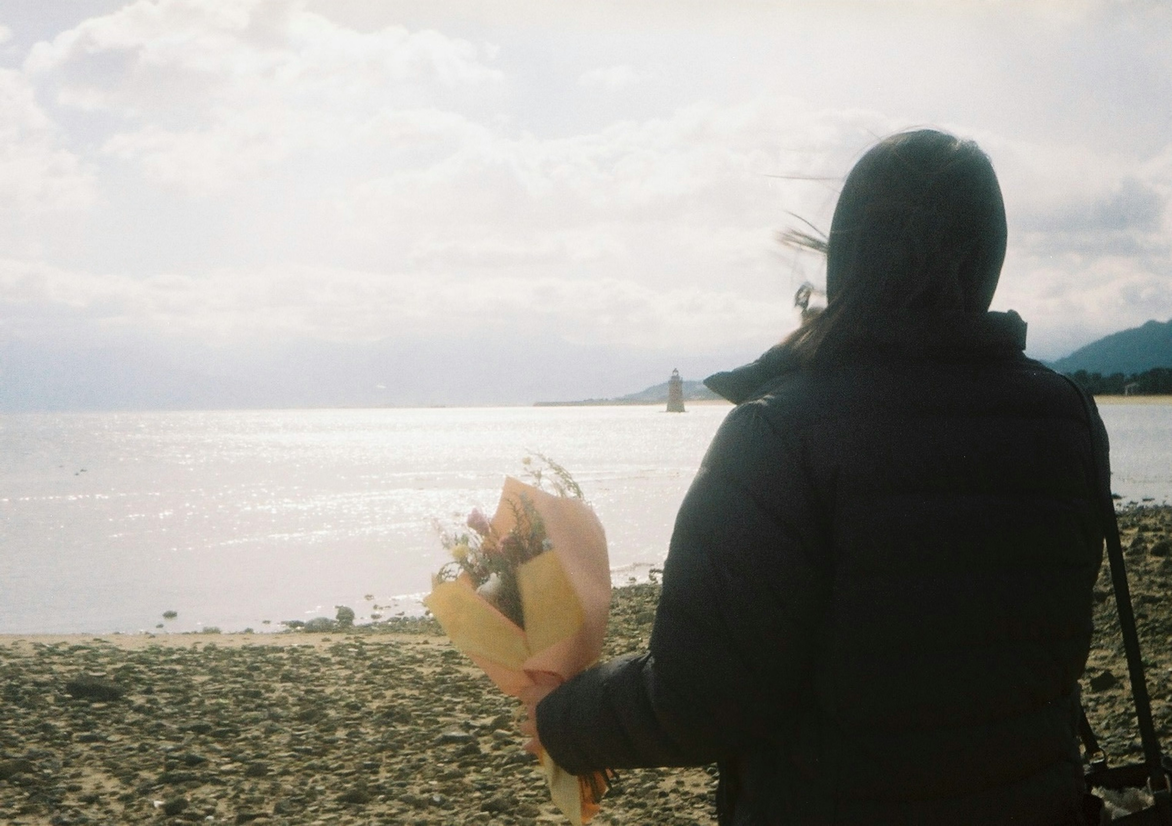 海辺で花束を持つ人物の後ろ姿