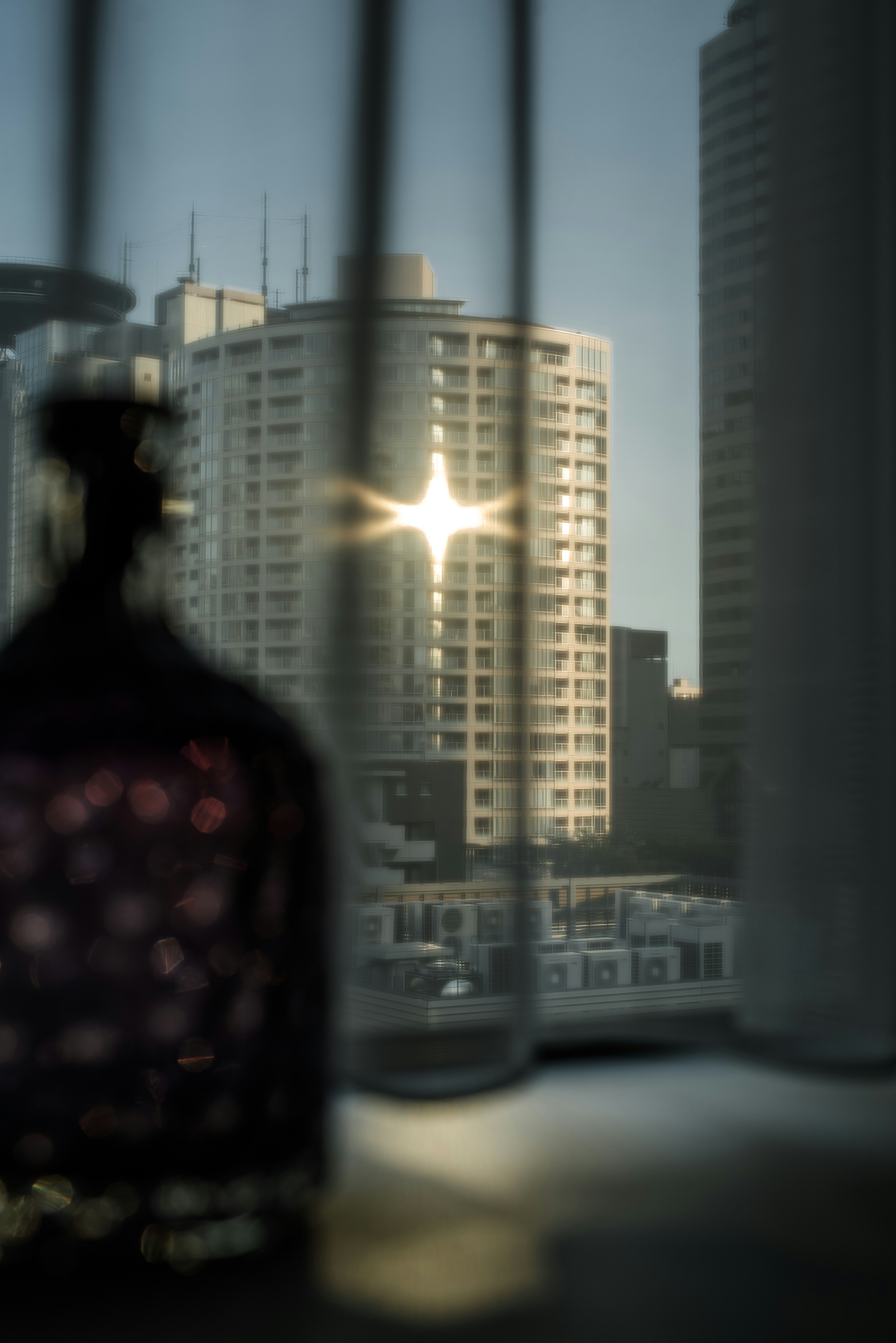 Silueta de una botella con la luz del sol reflejándose en un edificio