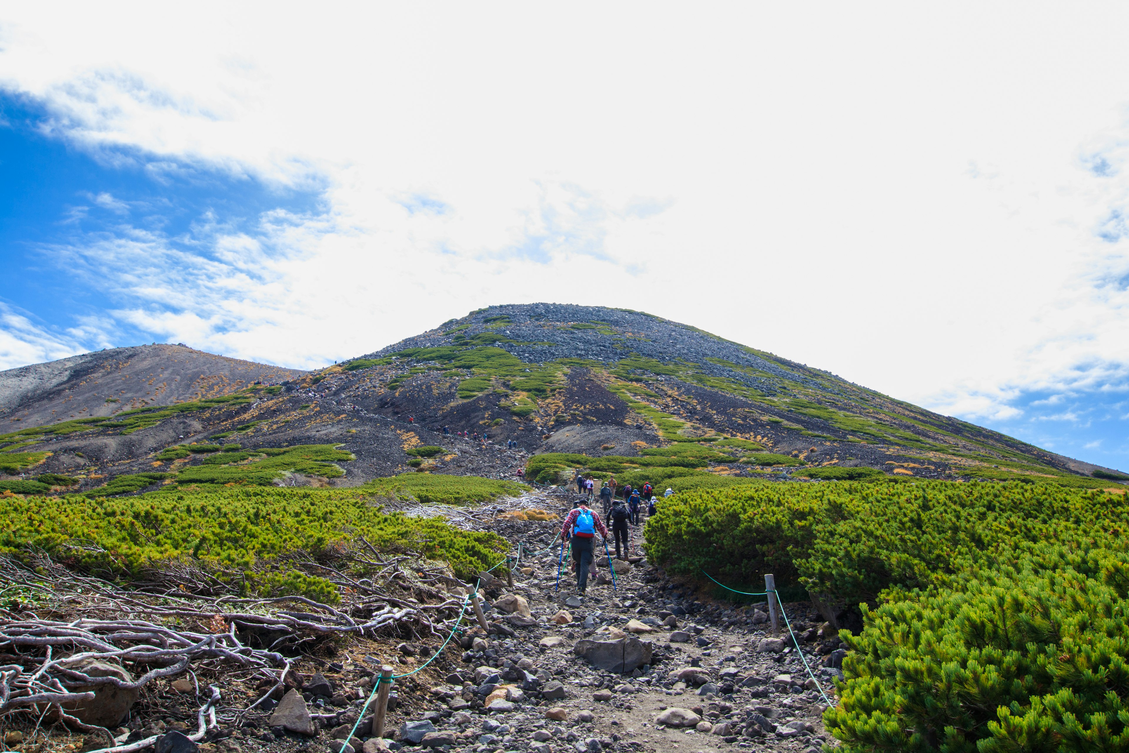 Randonneurs sur un sentier menant à une montagne sous un ciel dégagé