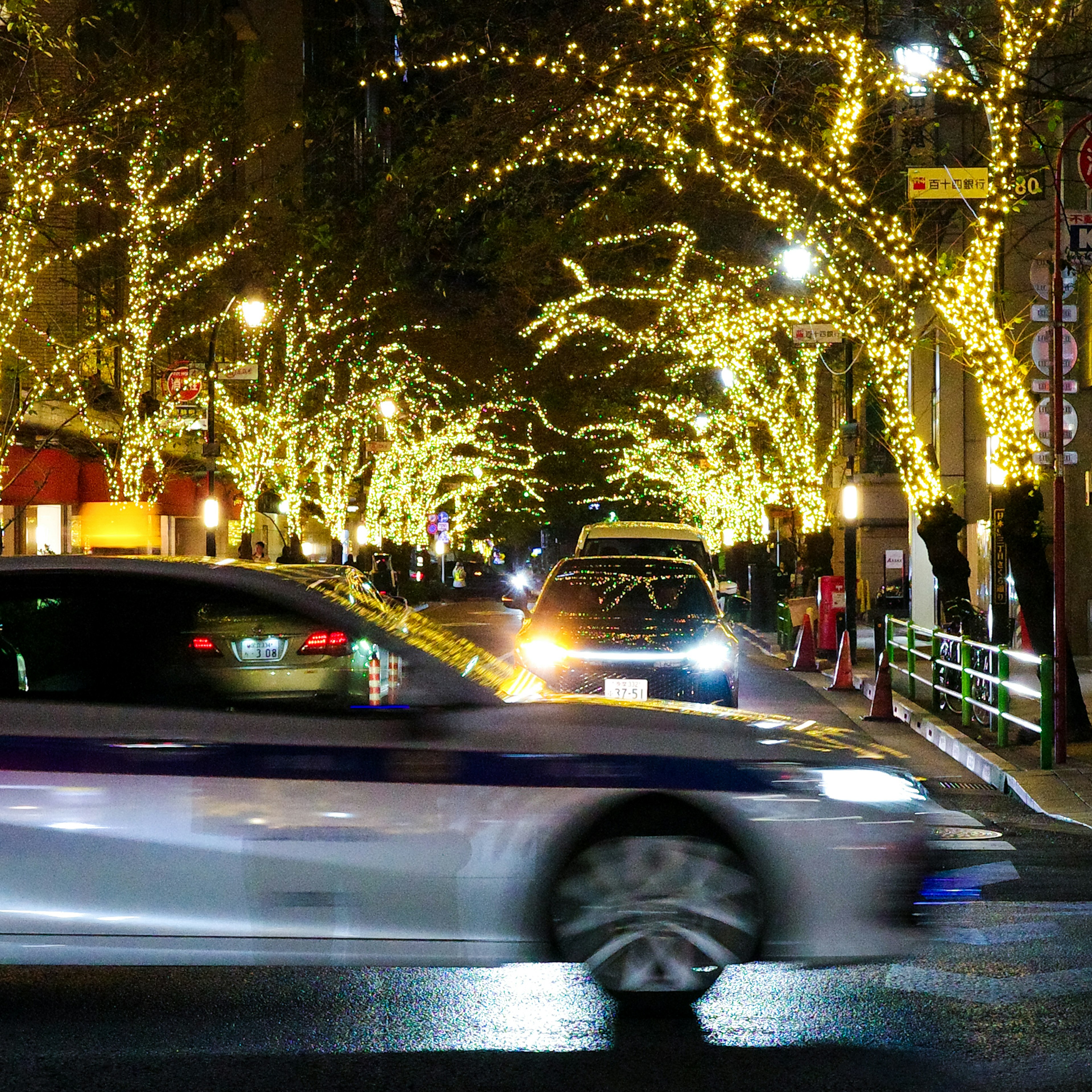 City street illuminated by festive lights with moving taxis